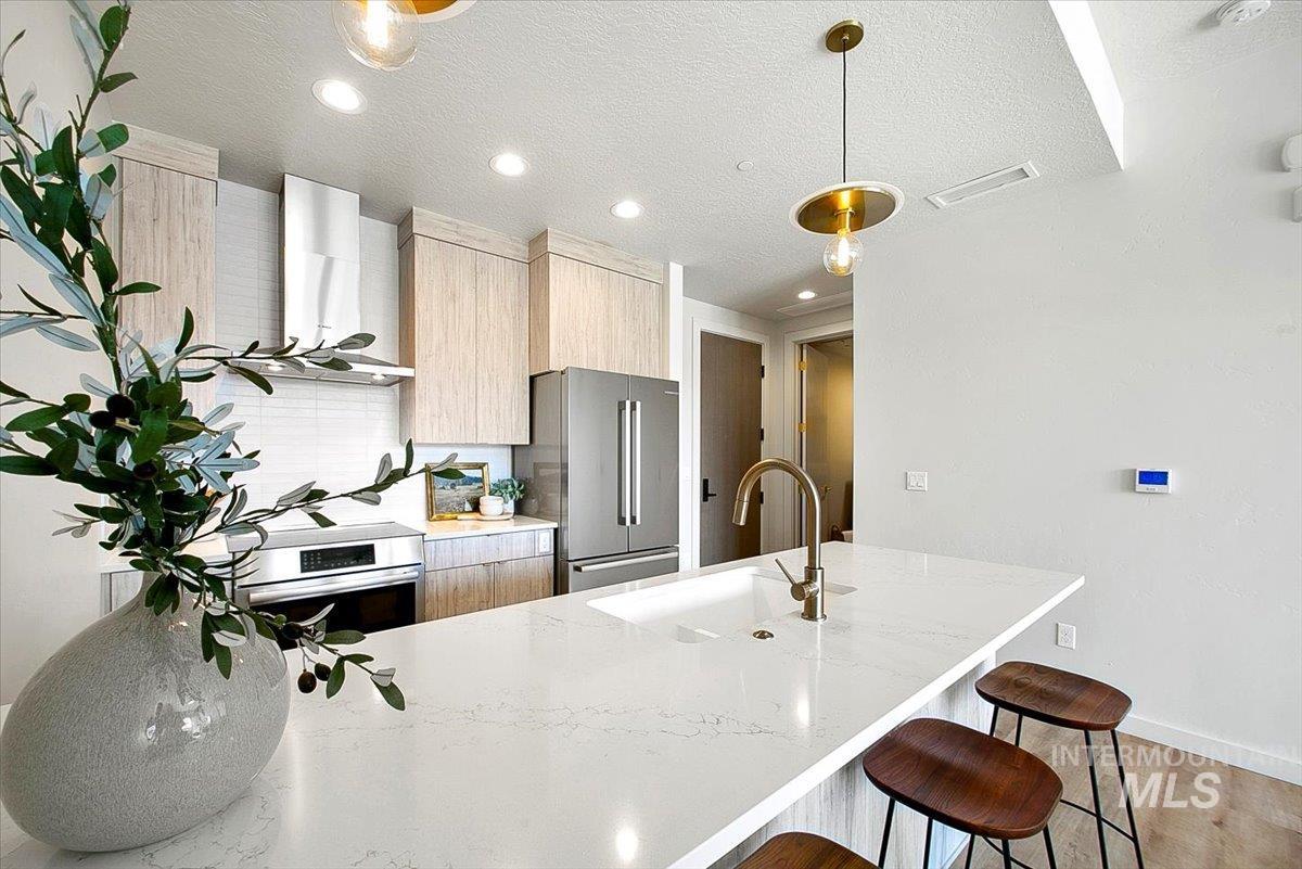 Kitchen featuring a peninsula, a textured ceiling, light stone counters, a breakfast bar, and modern cabinets
