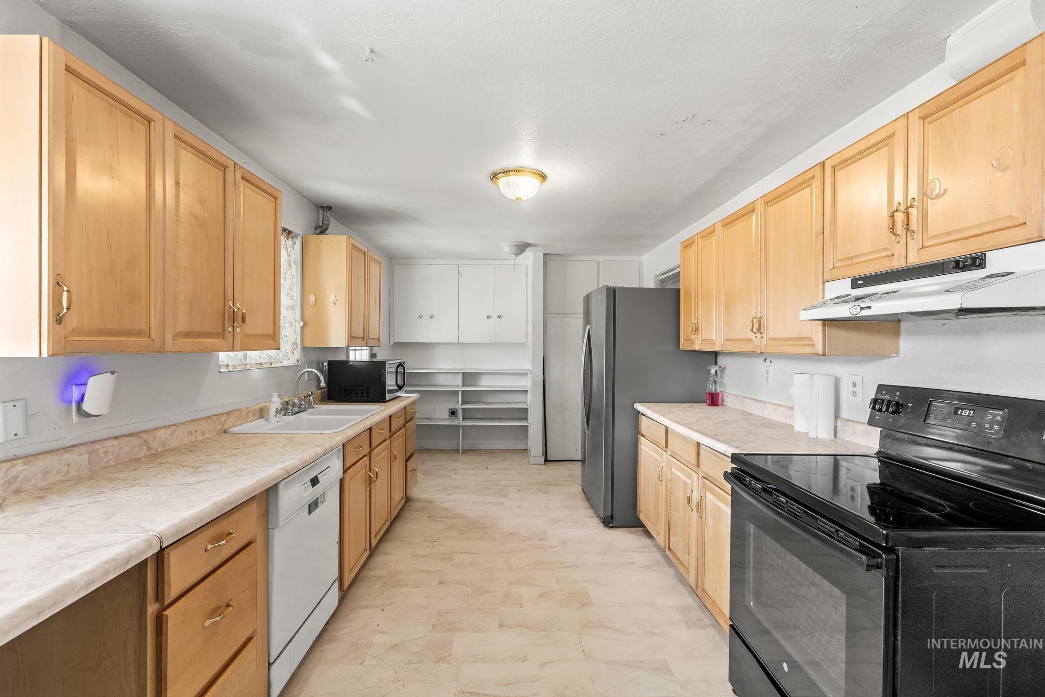 Kitchen featuring black electric range oven, light countertops, under cabinet range hood, and dishwasher