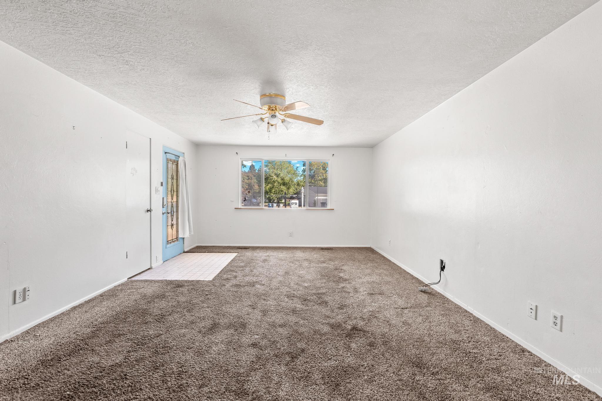 Carpeted spare room featuring a textured ceiling and a ceiling fan