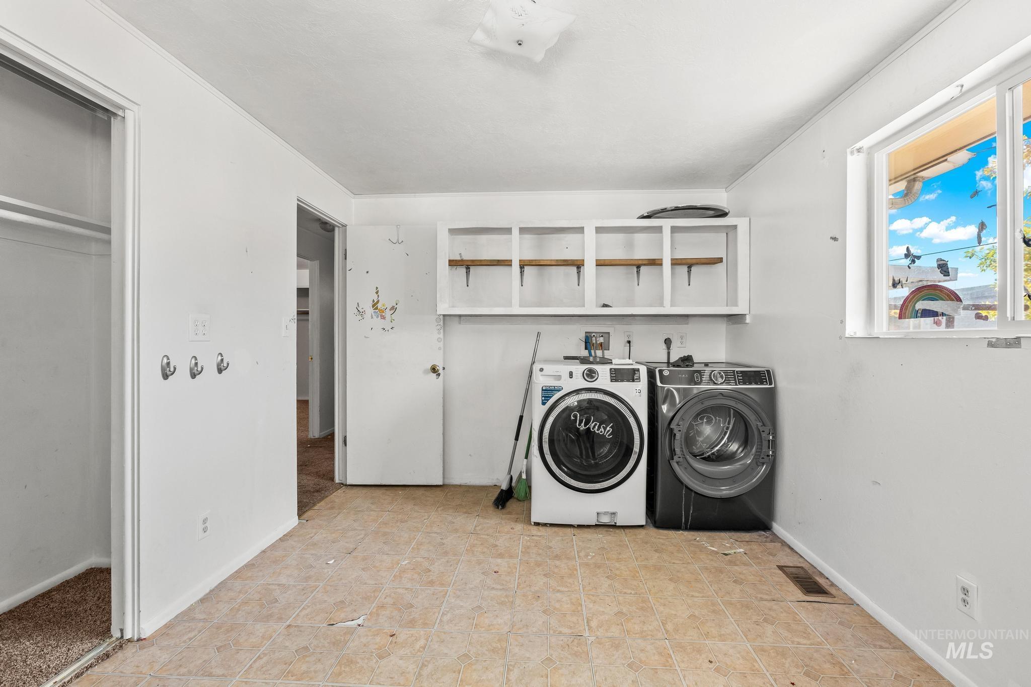 Laundry room with washer and dryer and light tile patterned flooring