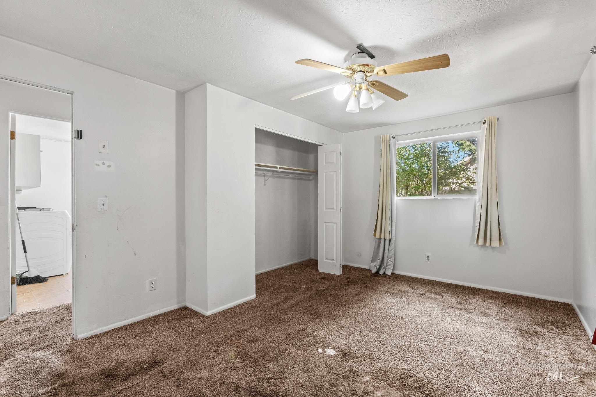 Unfurnished bedroom featuring carpet, a closet, a ceiling fan, and a textured ceiling