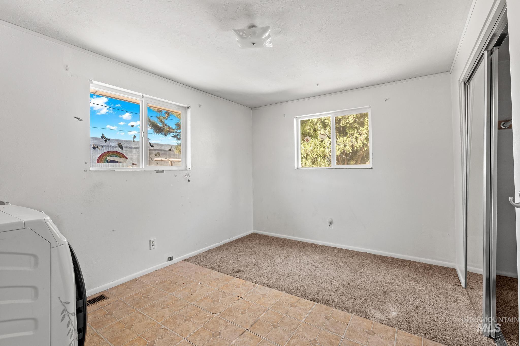 Unfurnished bedroom featuring light colored carpet, light tile patterned floors, a closet, and washer and dryer