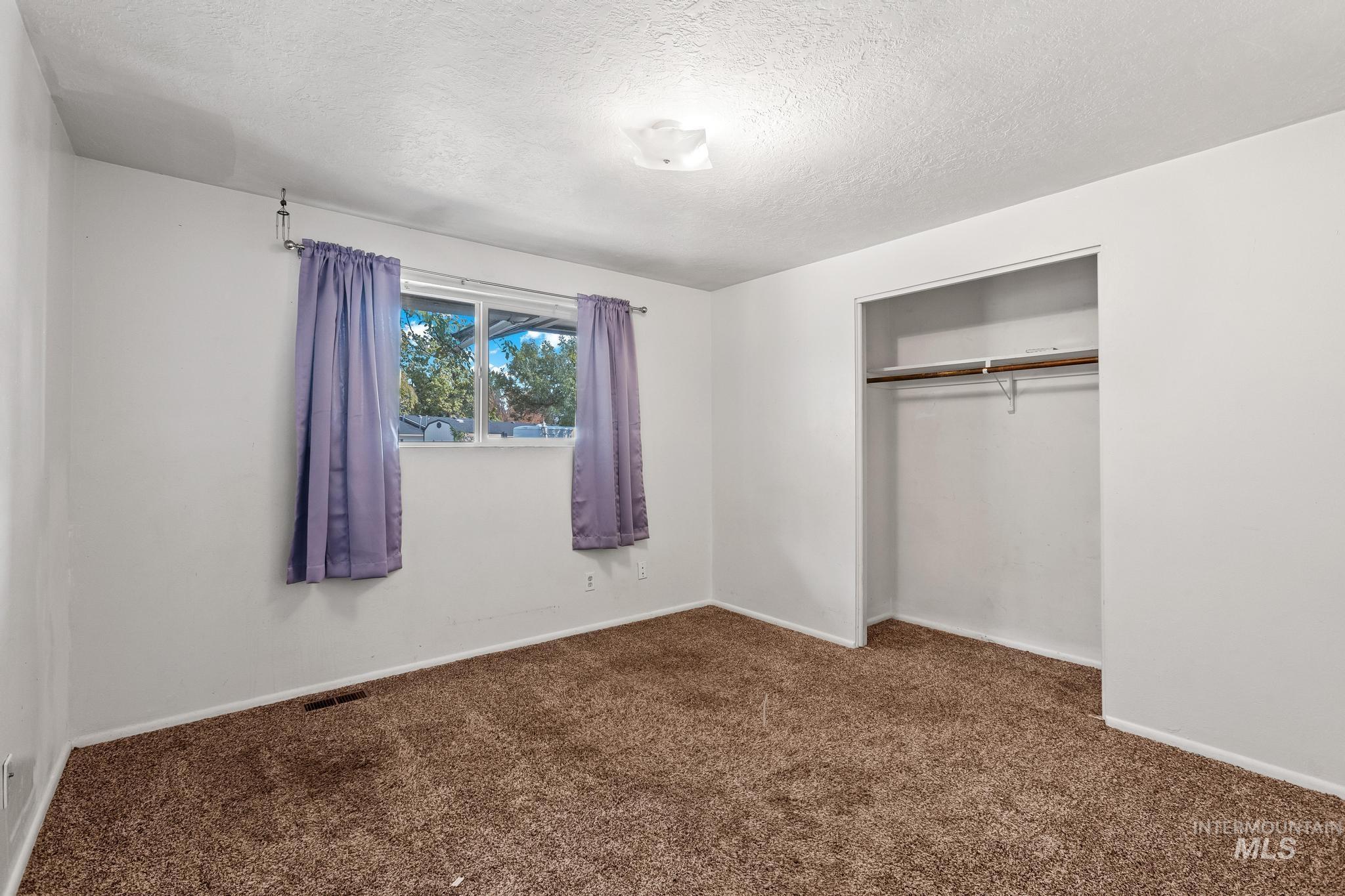 Unfurnished bedroom with dark carpet, a closet, and a textured ceiling
