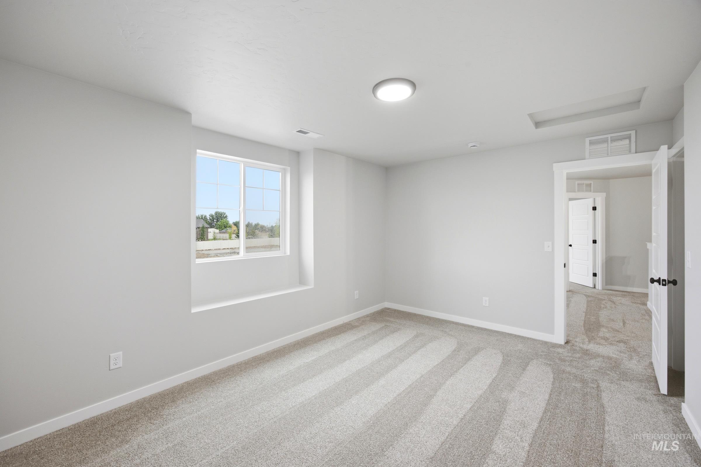 Carpeted interior space featuring neutral wall tones, a large window, white trim, and a flush-mount ceiling light