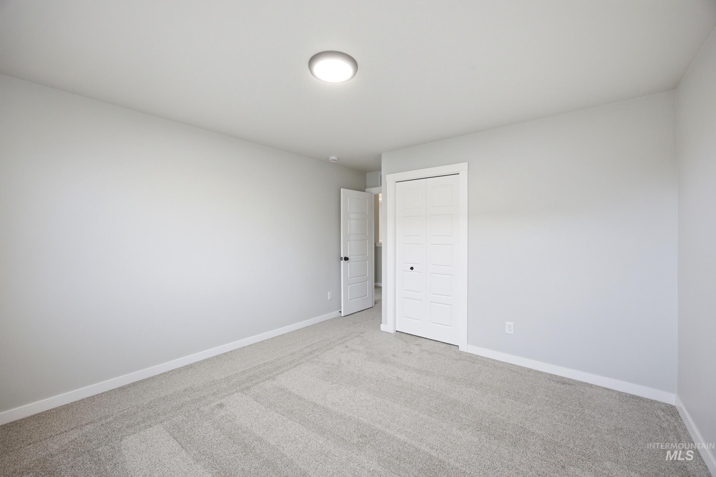 Carpeted room with light gray walls, white baseboards, and a flush mount ceiling light