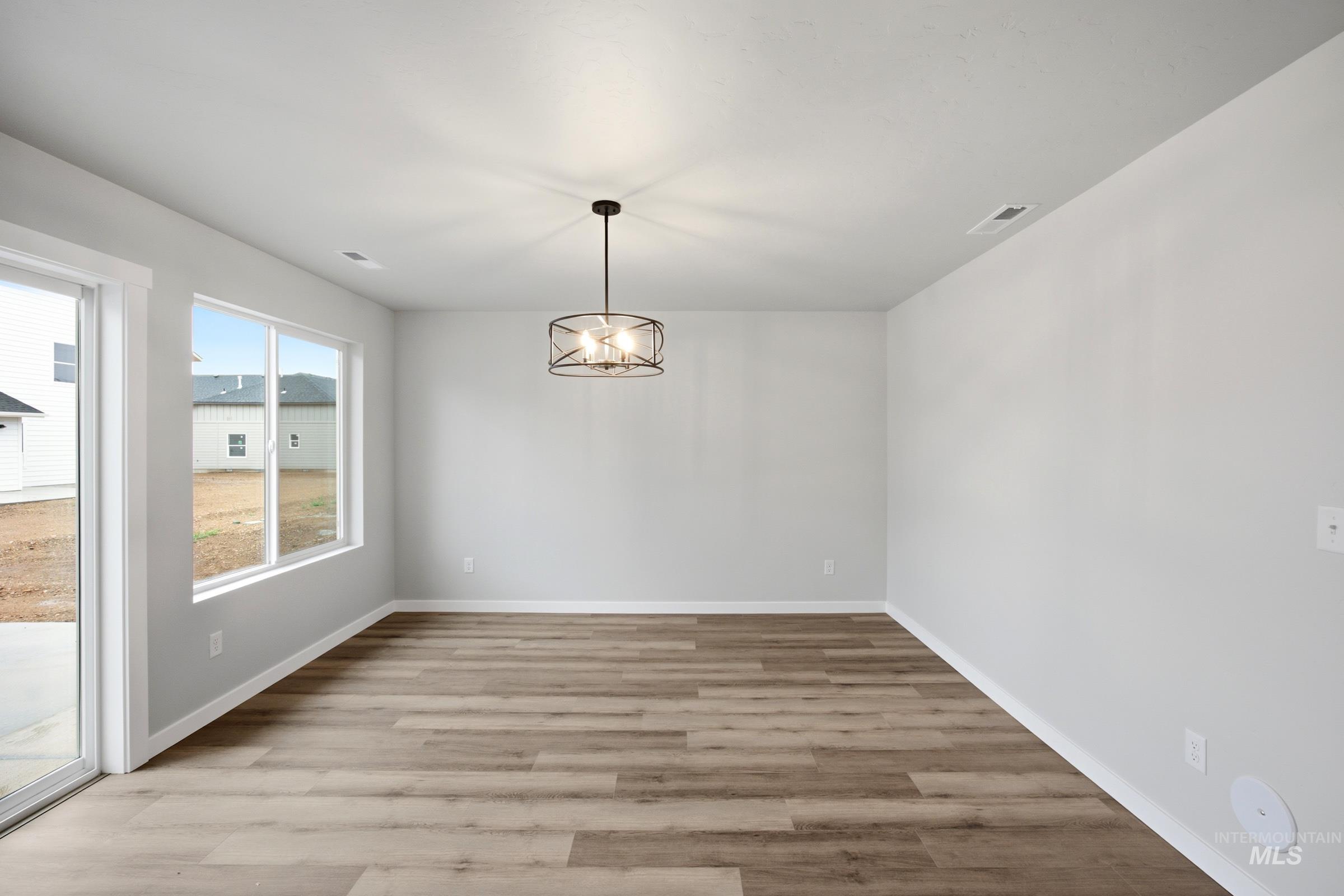 Expansive room featuring wood-finish flooring, a contemporary drum chandelier, and a sliding glass door providing outdoor access