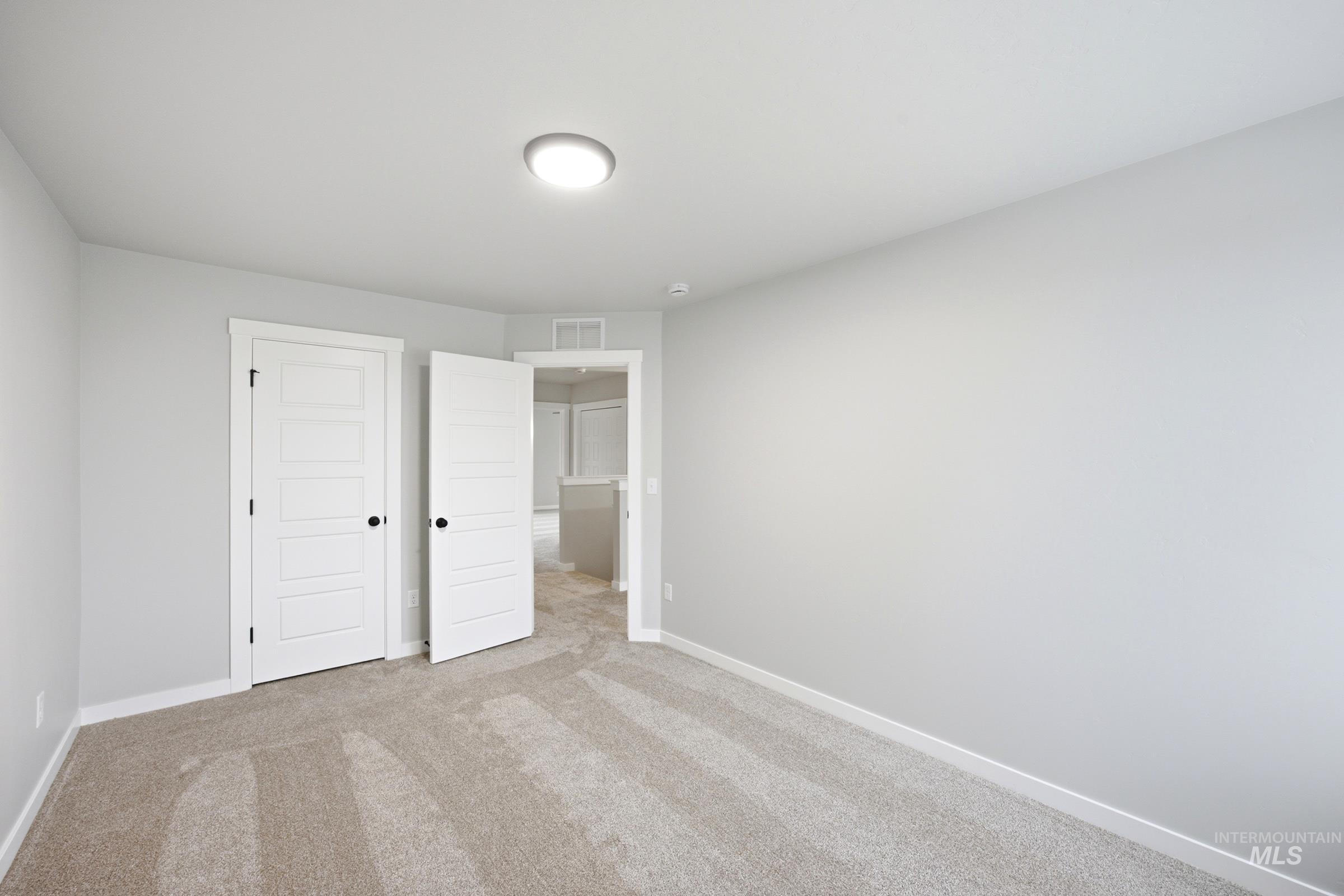 Carpeted interior space with light gray walls, white trim, and a flush-mount ceiling light