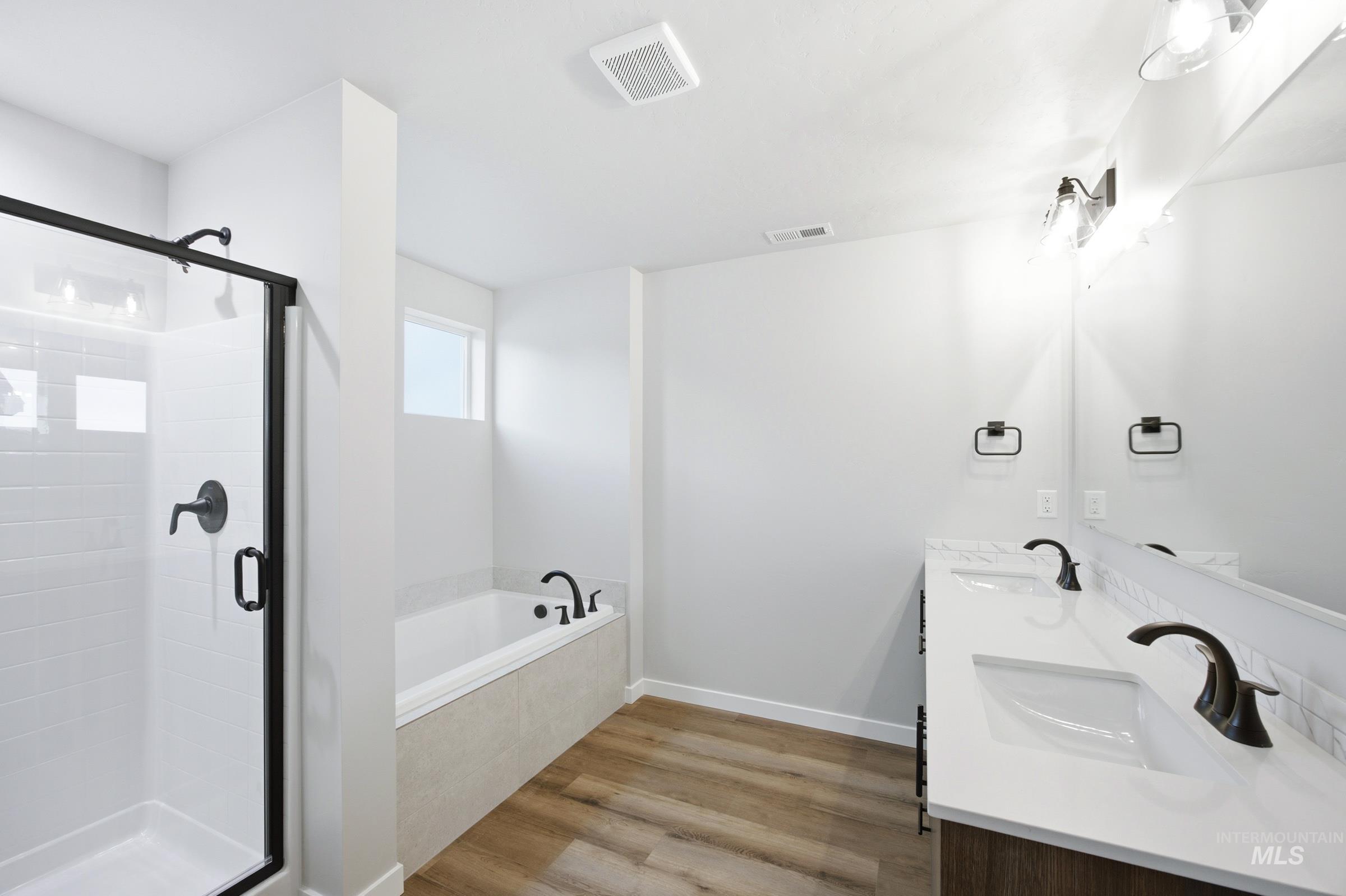 Contemporary bathroom featuring a dual vanity with white countertops, integrated sinks, and matte black fixtures