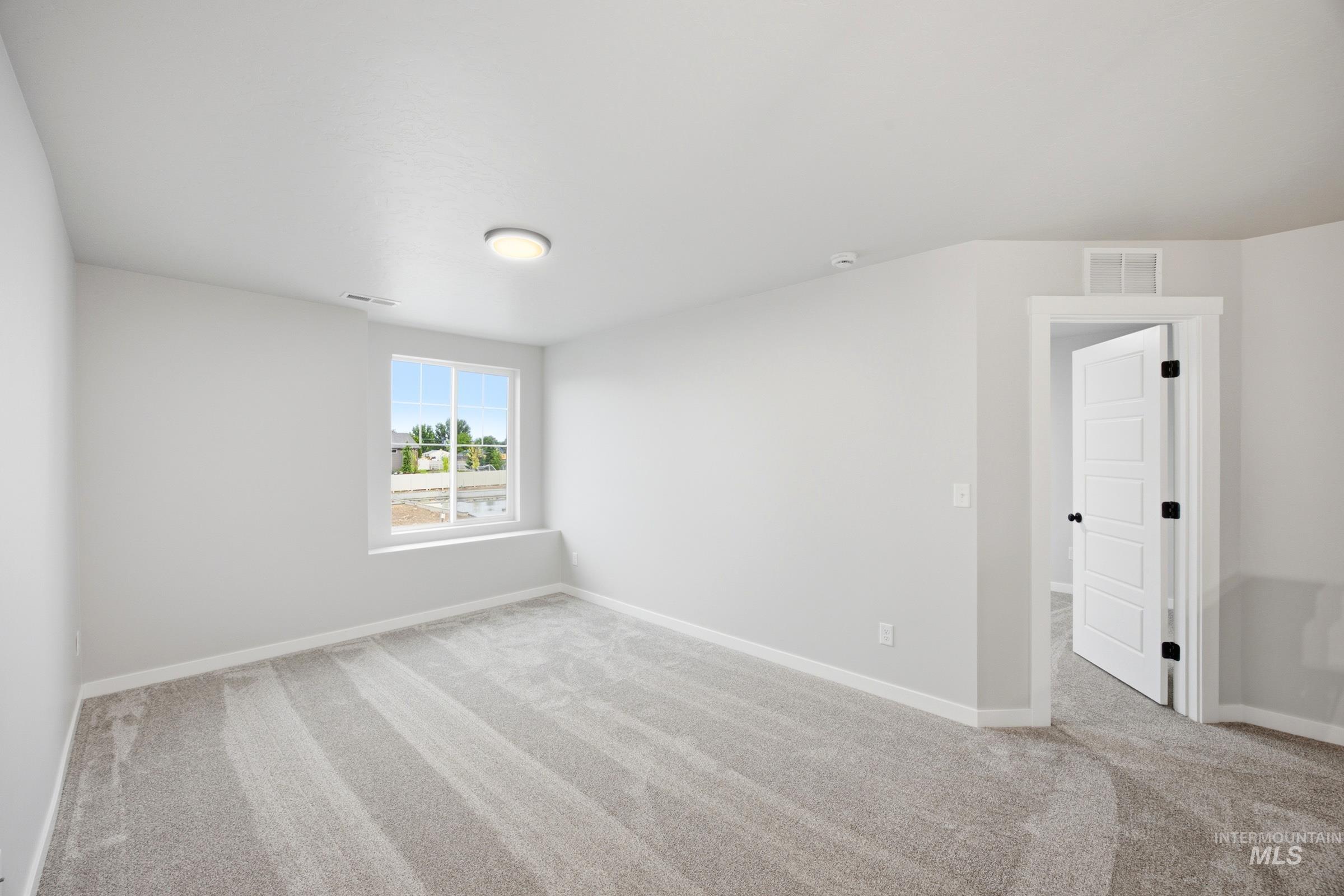 Spacious room featuring neutral carpeting and light gray wall tones