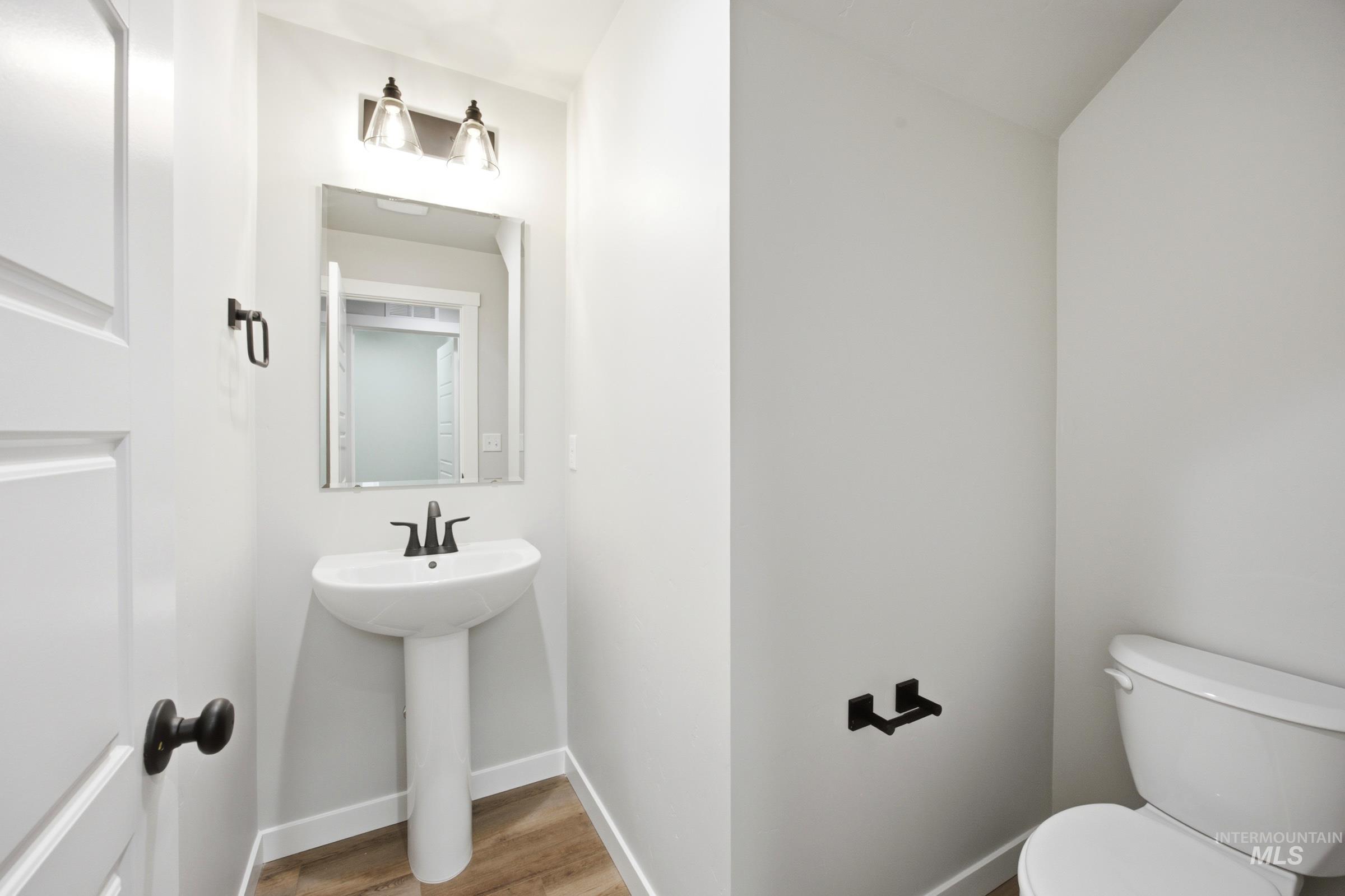 Pedestal sink with dark bronze faucet, framed mirror, and two-light vanity fixture