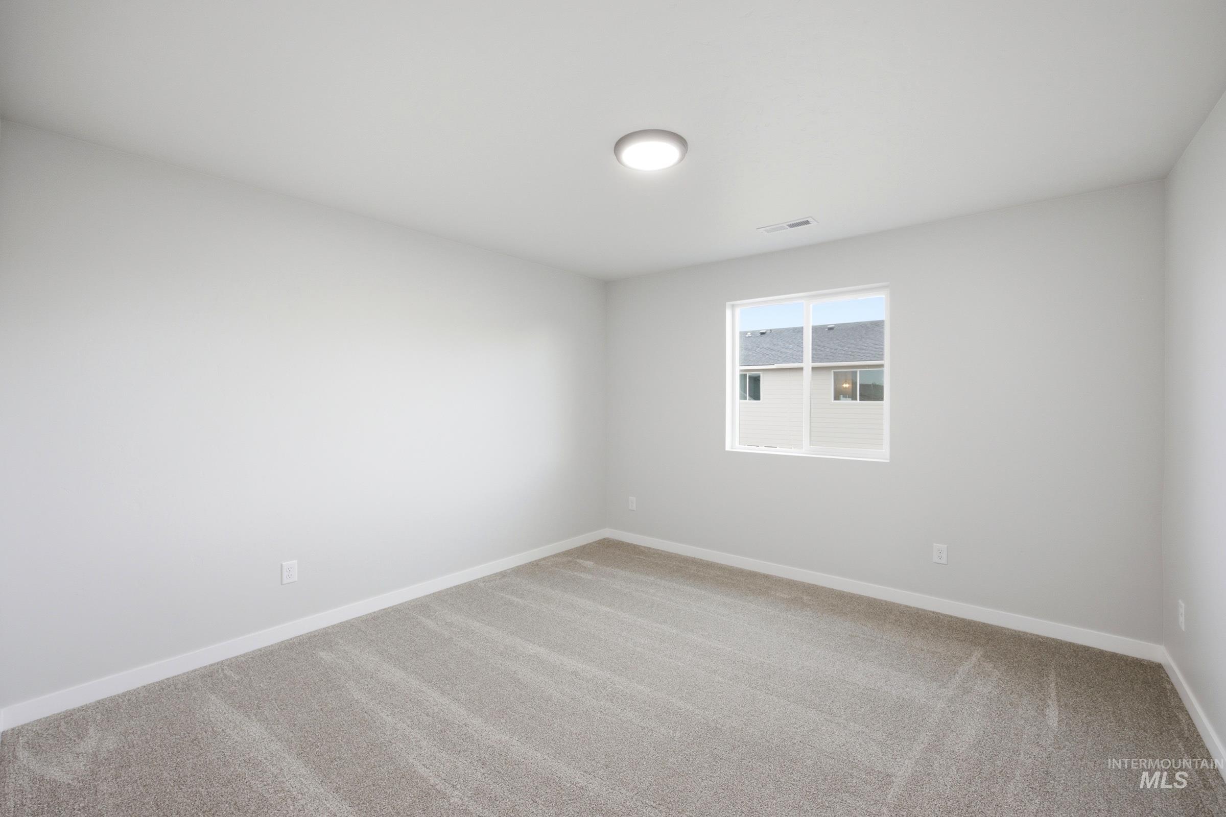 Neutral tone wall paint with white trim, light-colored carpet flooring, recessed ceiling light, and a white-framed window