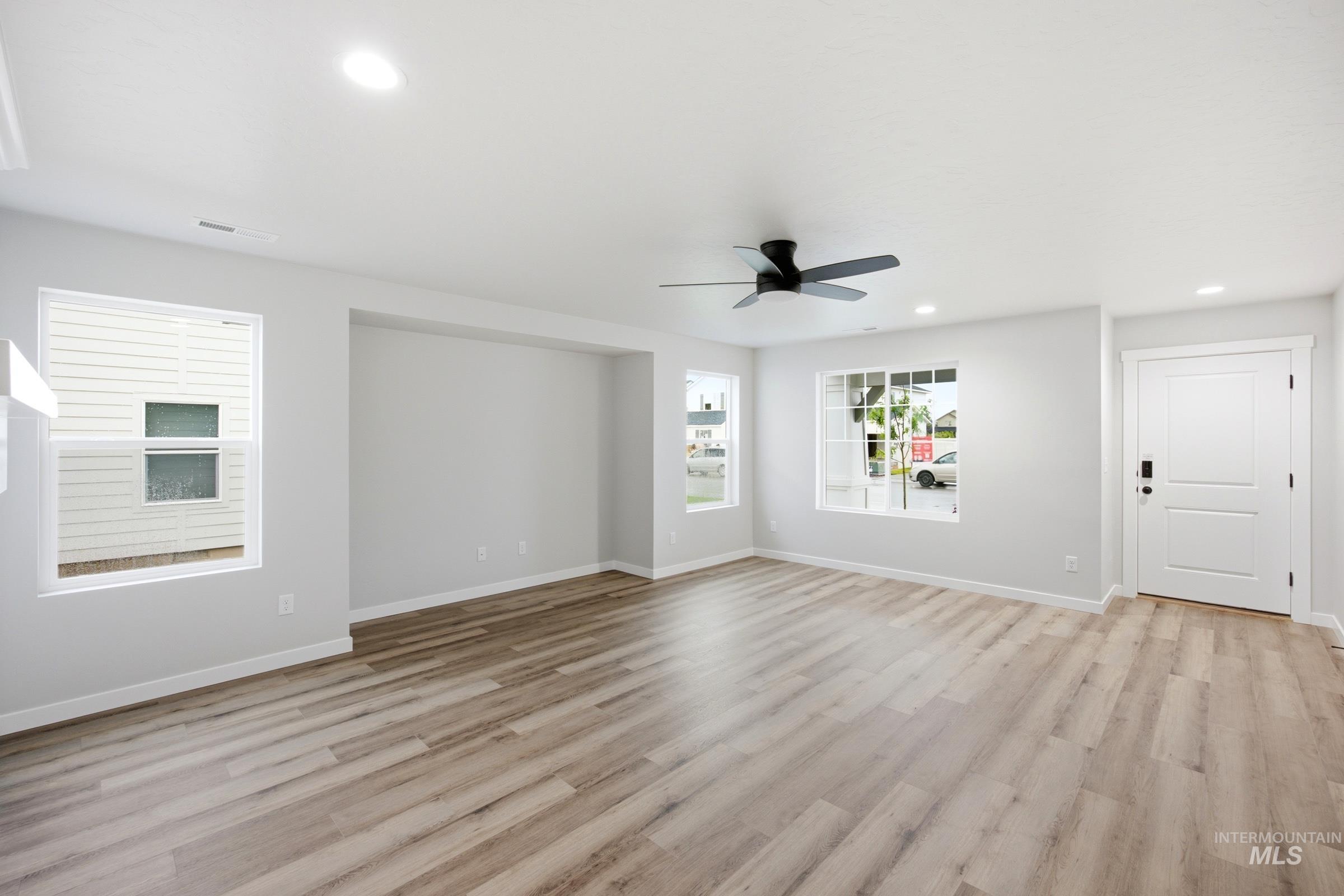 Spacious living area featuring wood-finish flooring, recessed lighting, and a modern ceiling fan