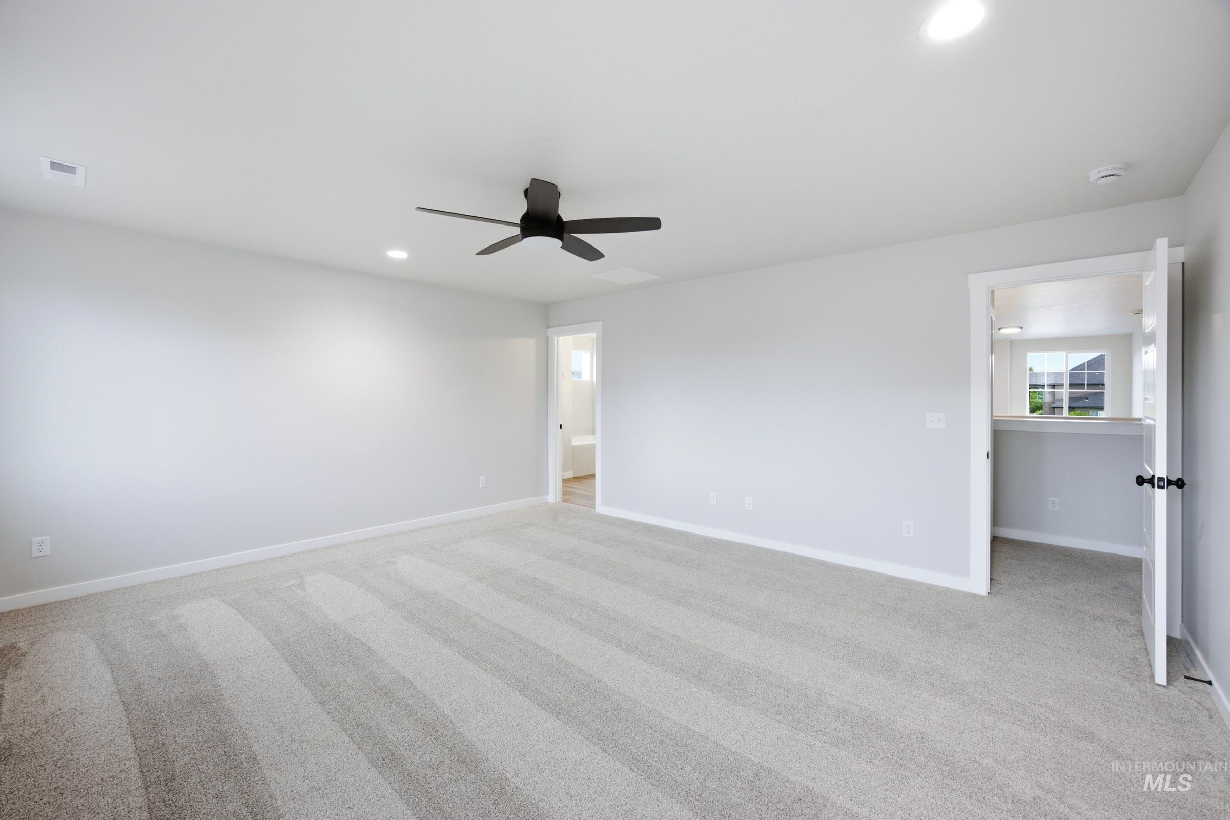 Spacious interior room featuring light-toned carpeting and white baseboards