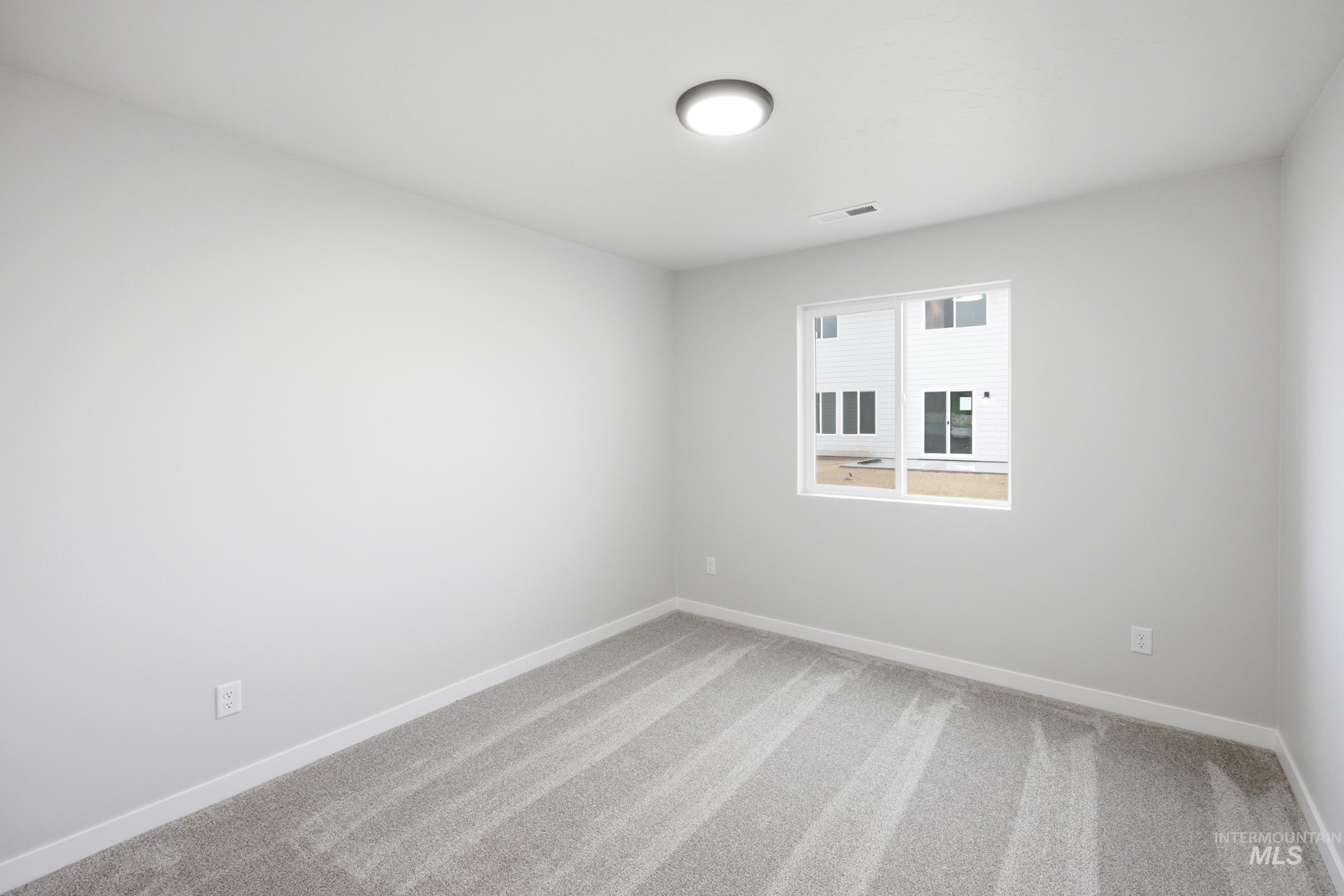 Carpeted room with a flush-mount ceiling light and a window featuring white trim