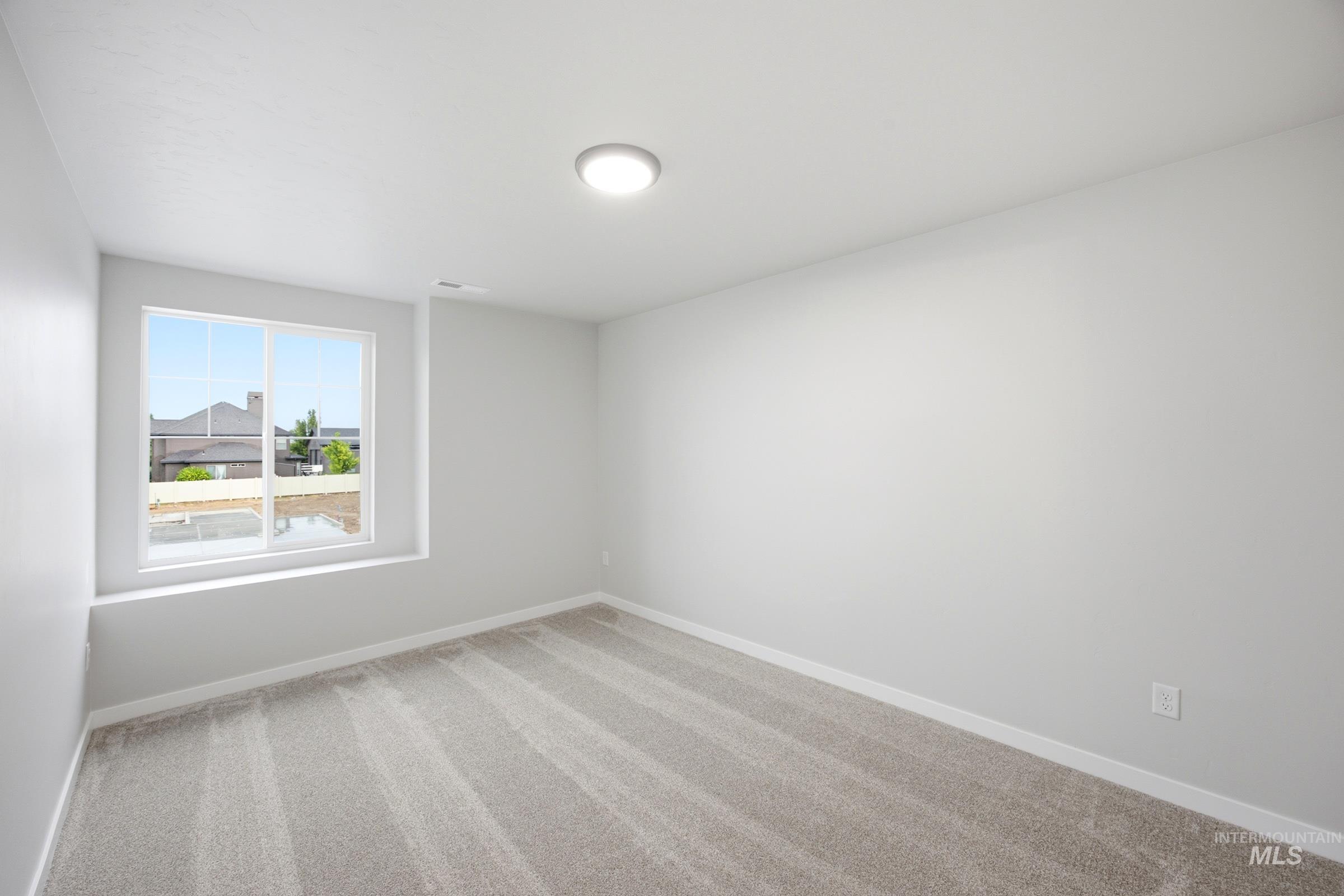 Bright room featuring neutral wall tones, plush gray carpet, a spacious window, white trim, and a flush-mount ceiling light