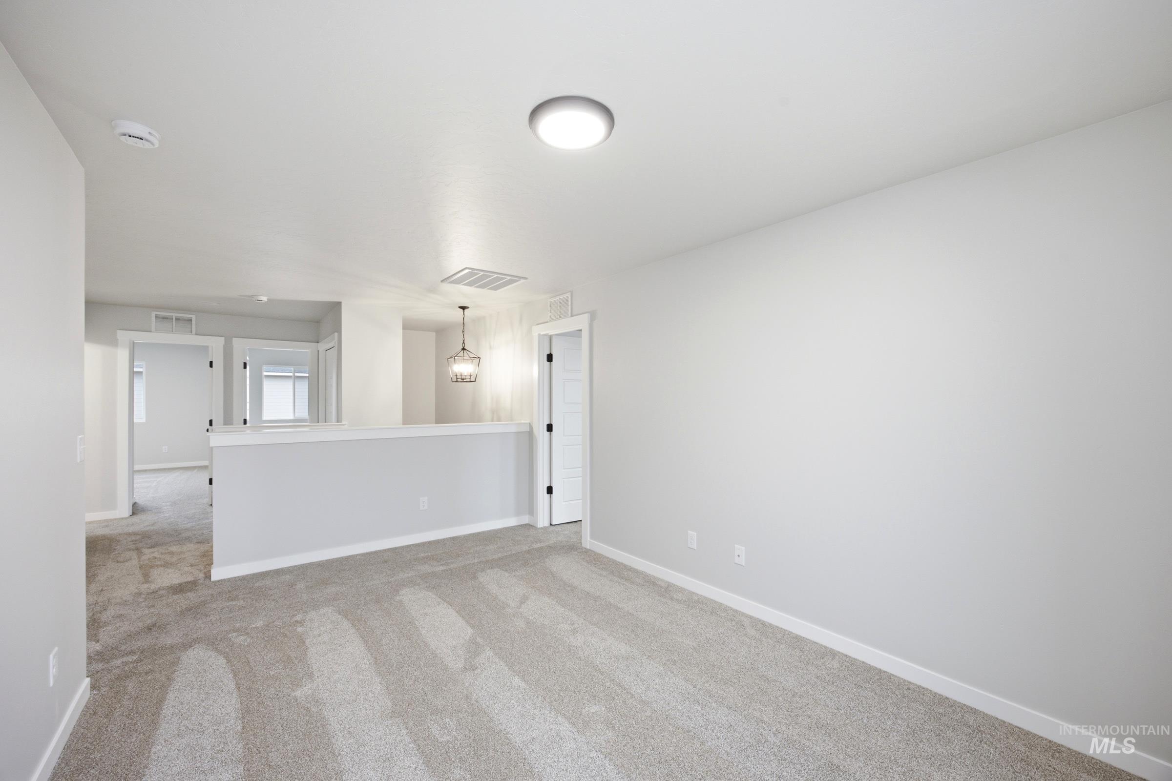 Open loft area featuring neutral-toned carpeting and light gray walls