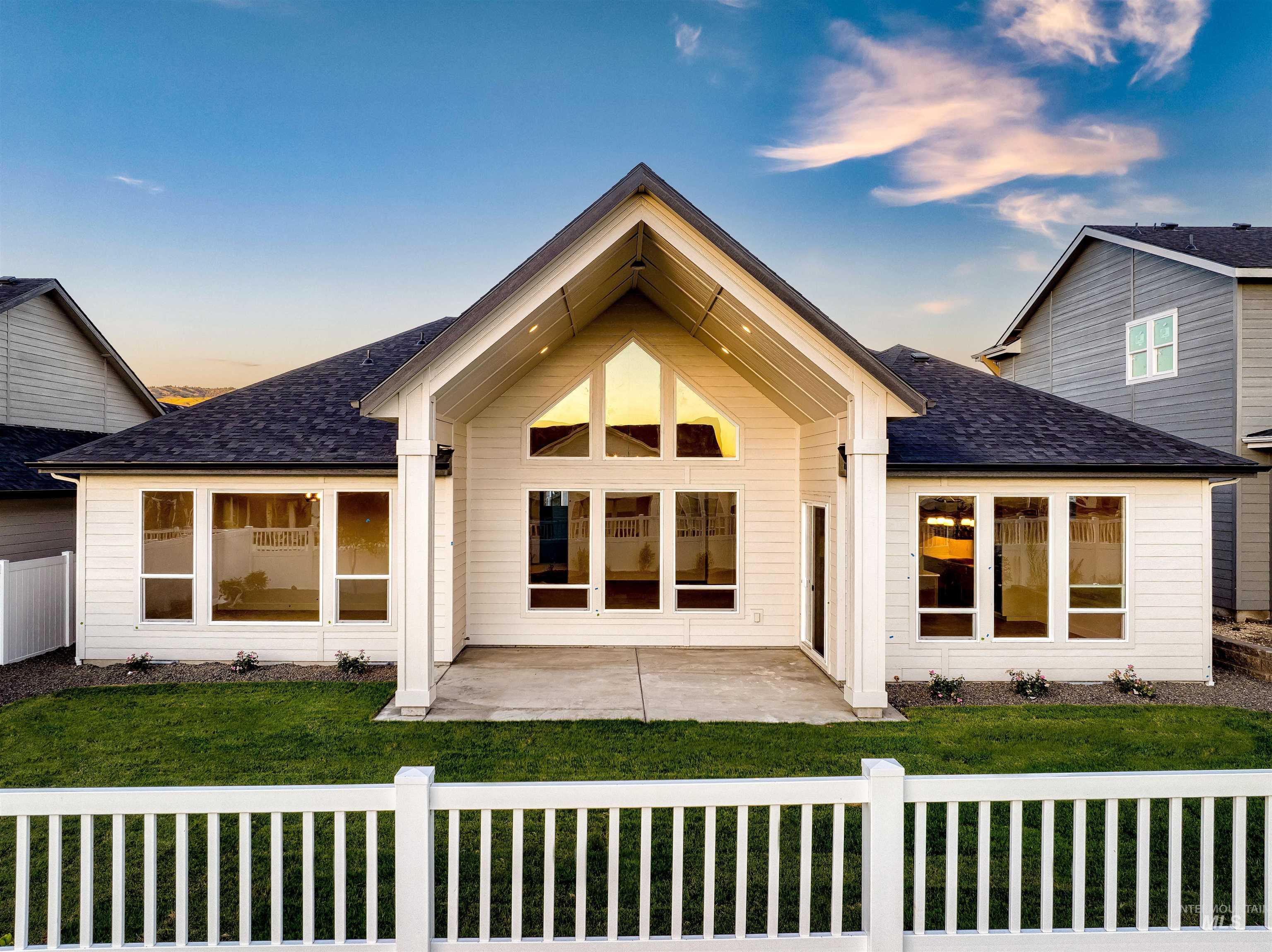 Back of house at dusk featuring a patio and roof with shingles