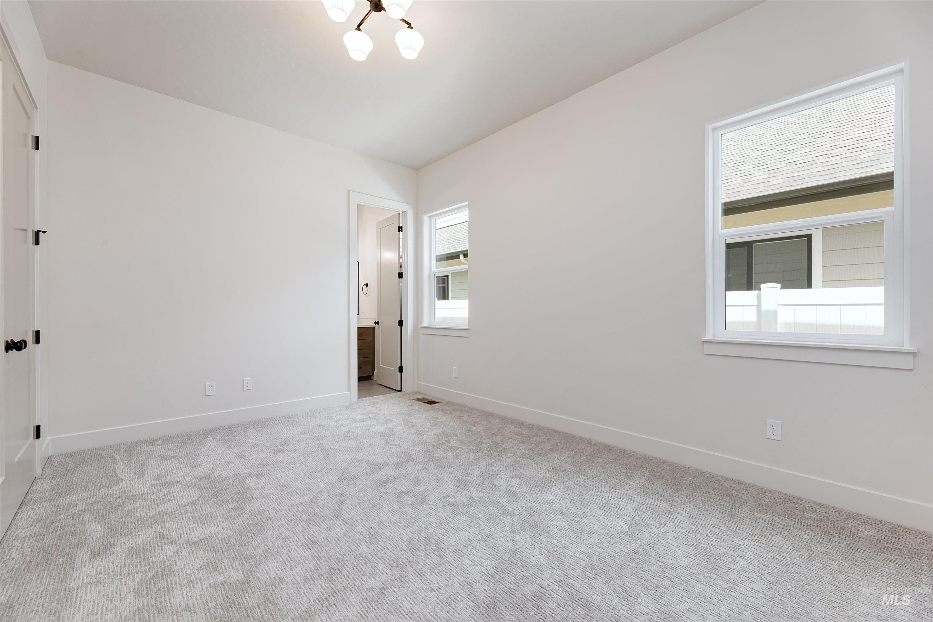 Unfurnished bedroom featuring a chandelier and carpet flooring