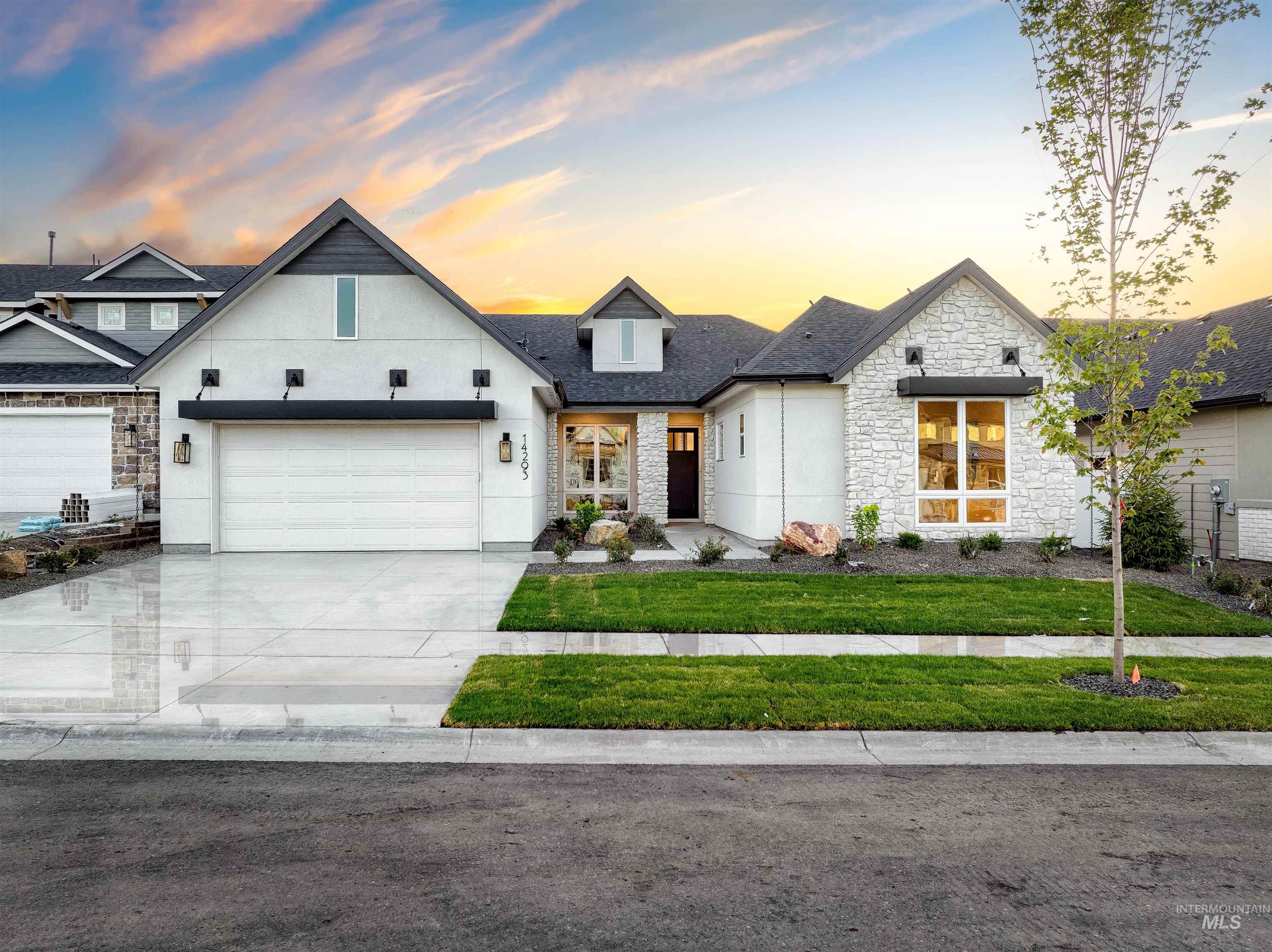View of front facade with stone siding, concrete driveway, a garage, a front lawn, and stucco siding