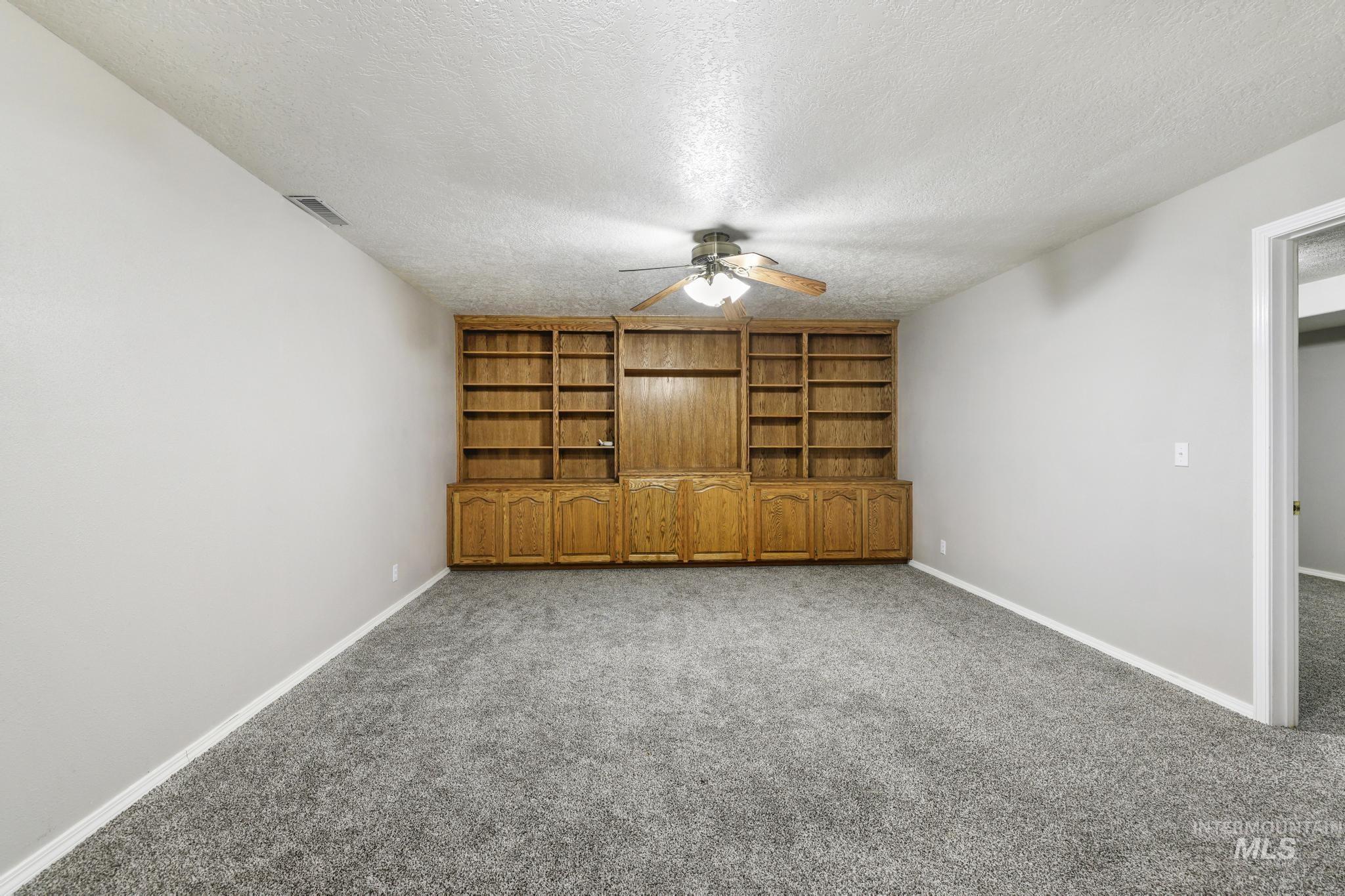 Spare room with a textured ceiling, carpet, and a ceiling fan