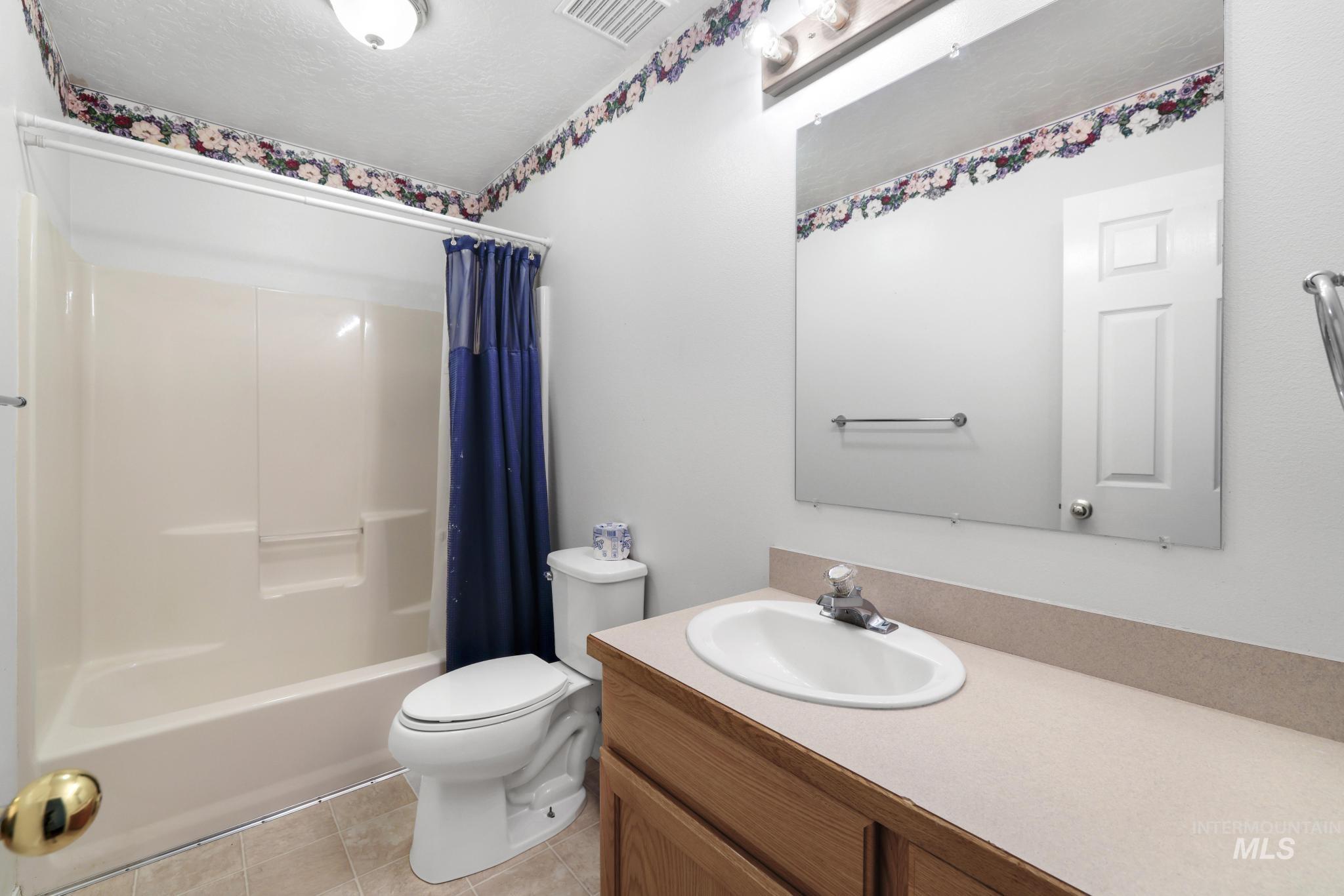 Full bathroom featuring vanity, shower / bath combo, light tile patterned floors, and a textured ceiling