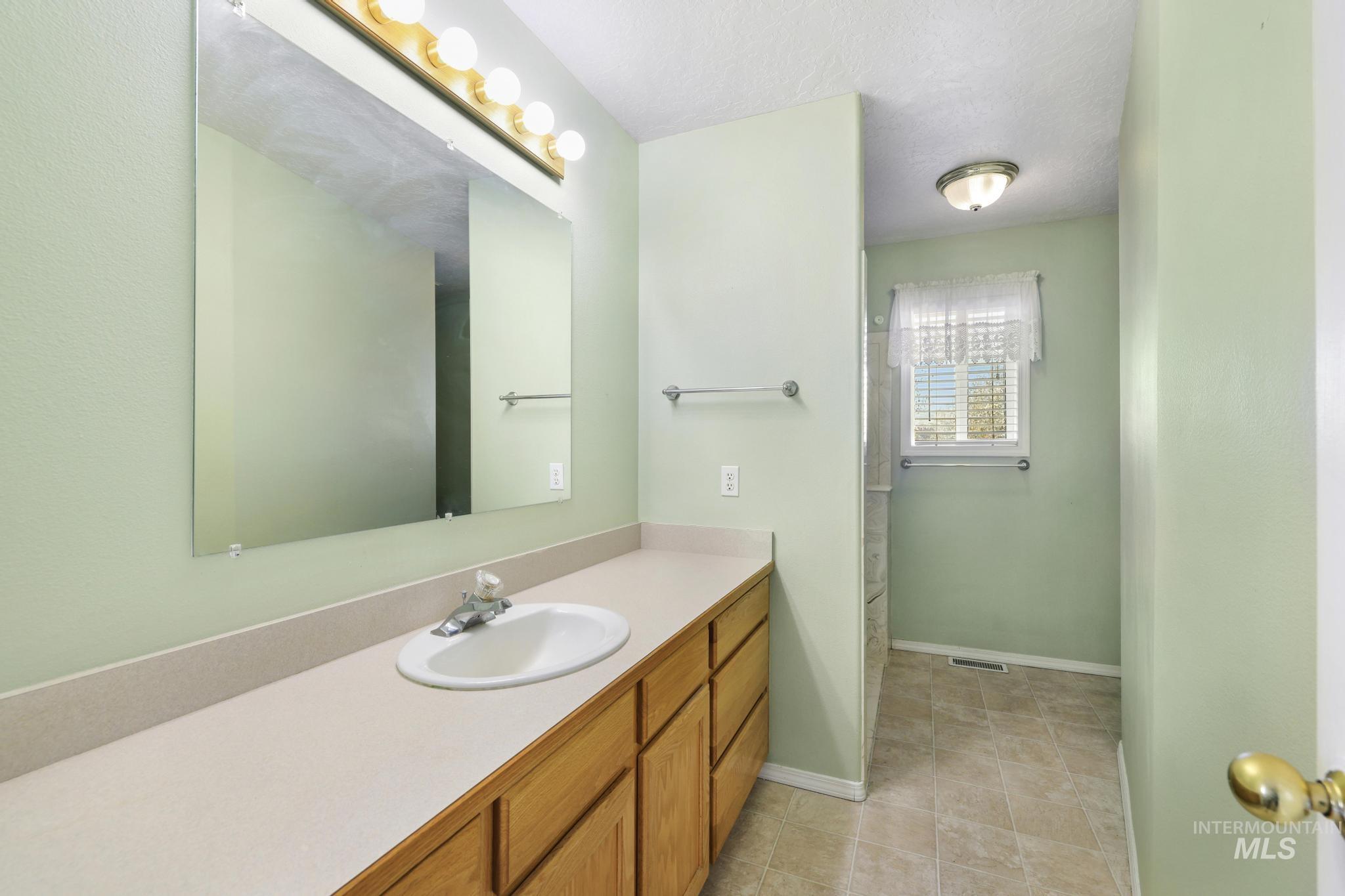 Full bath featuring a stall shower, vanity, a textured ceiling, and light tile patterned flooring