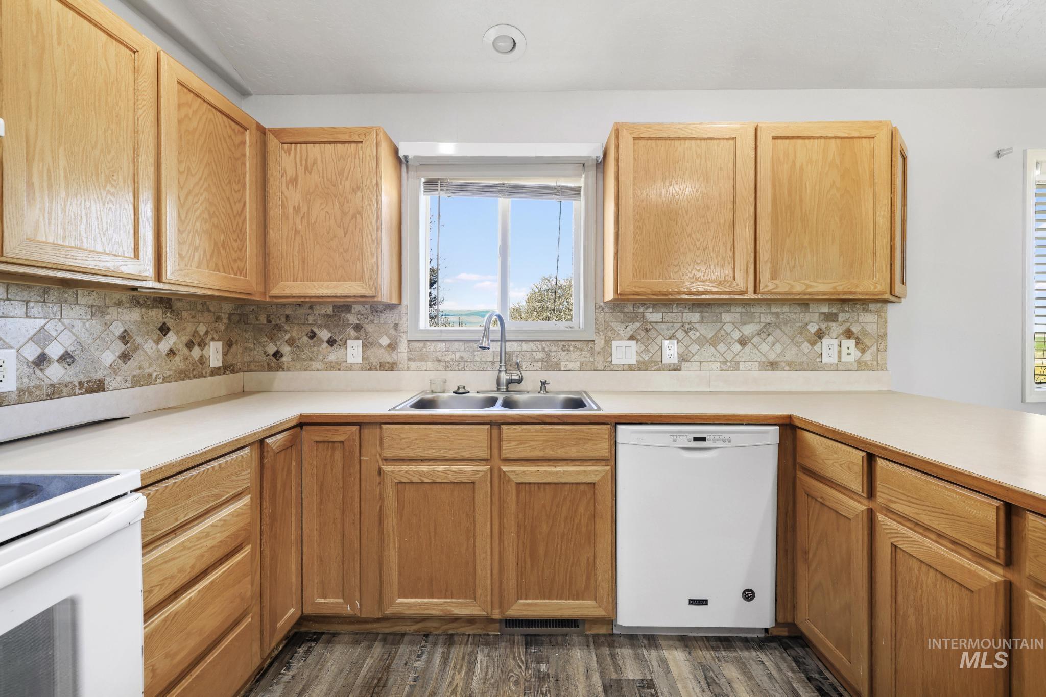 Kitchen with light countertops, white appliances, dark wood-style flooring, and light wood finish cabinets