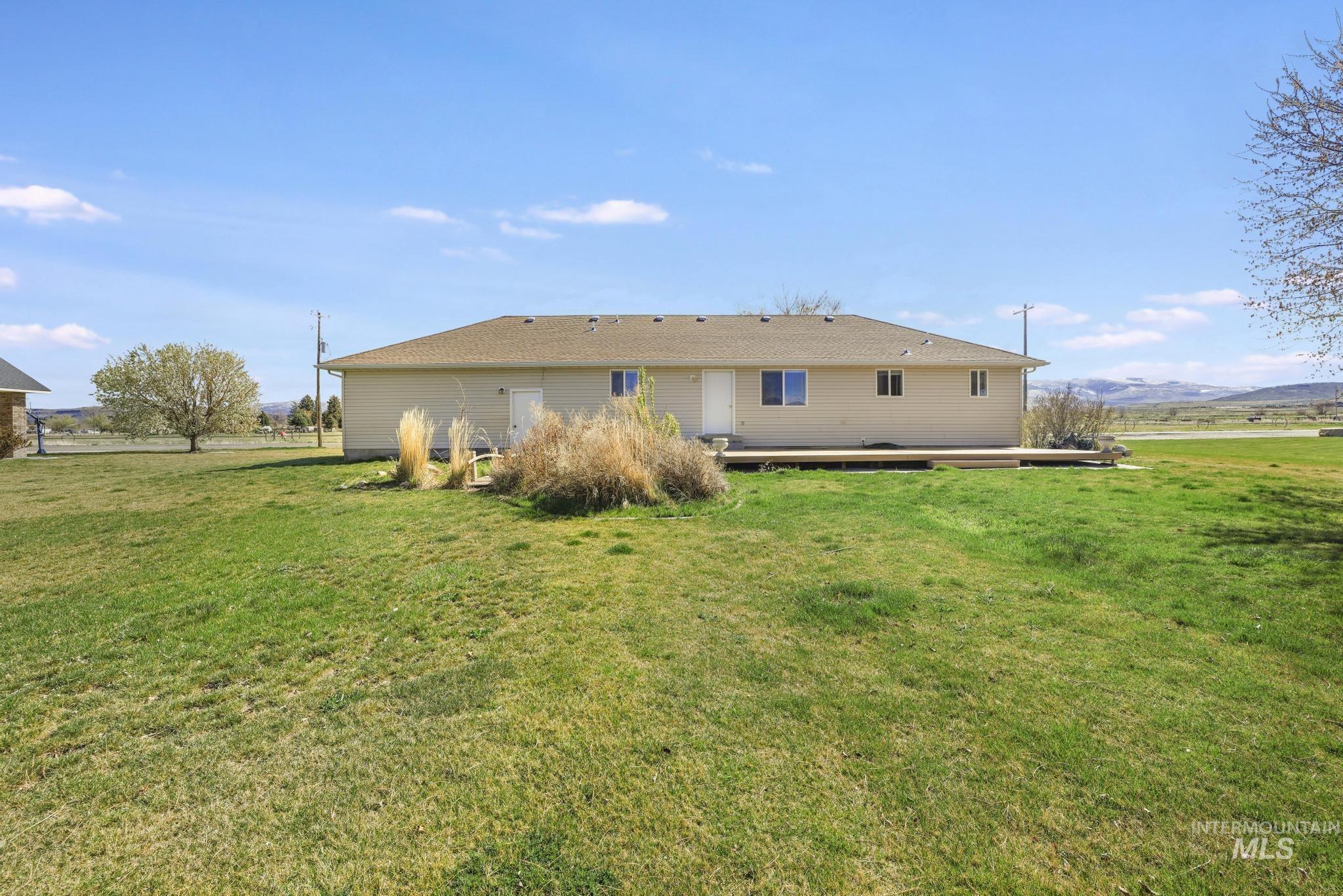 Rear view of property featuring a mountain view, a lawn, and a patio area