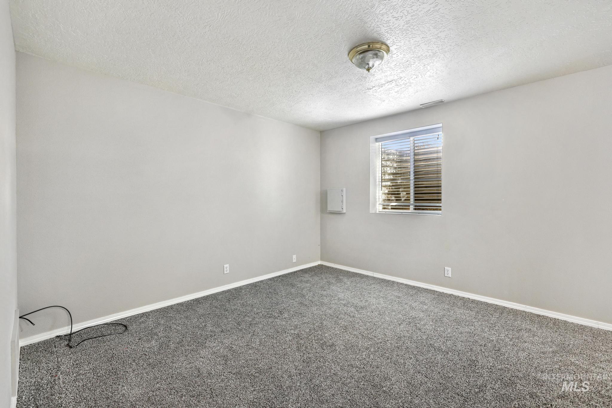 Spare room featuring dark carpet and a textured ceiling