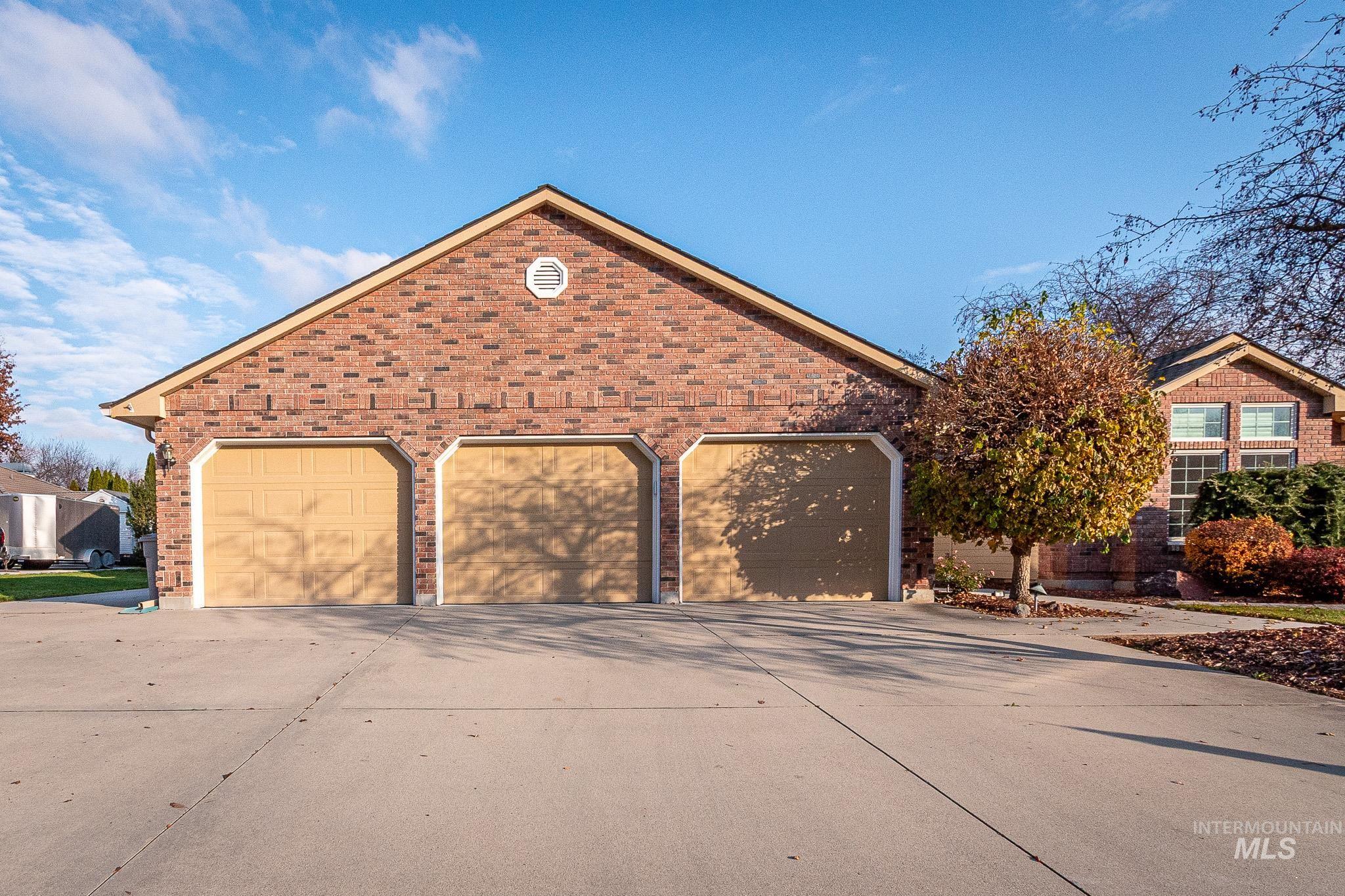 View of front of home featuring a garage, brick siding, and driveway