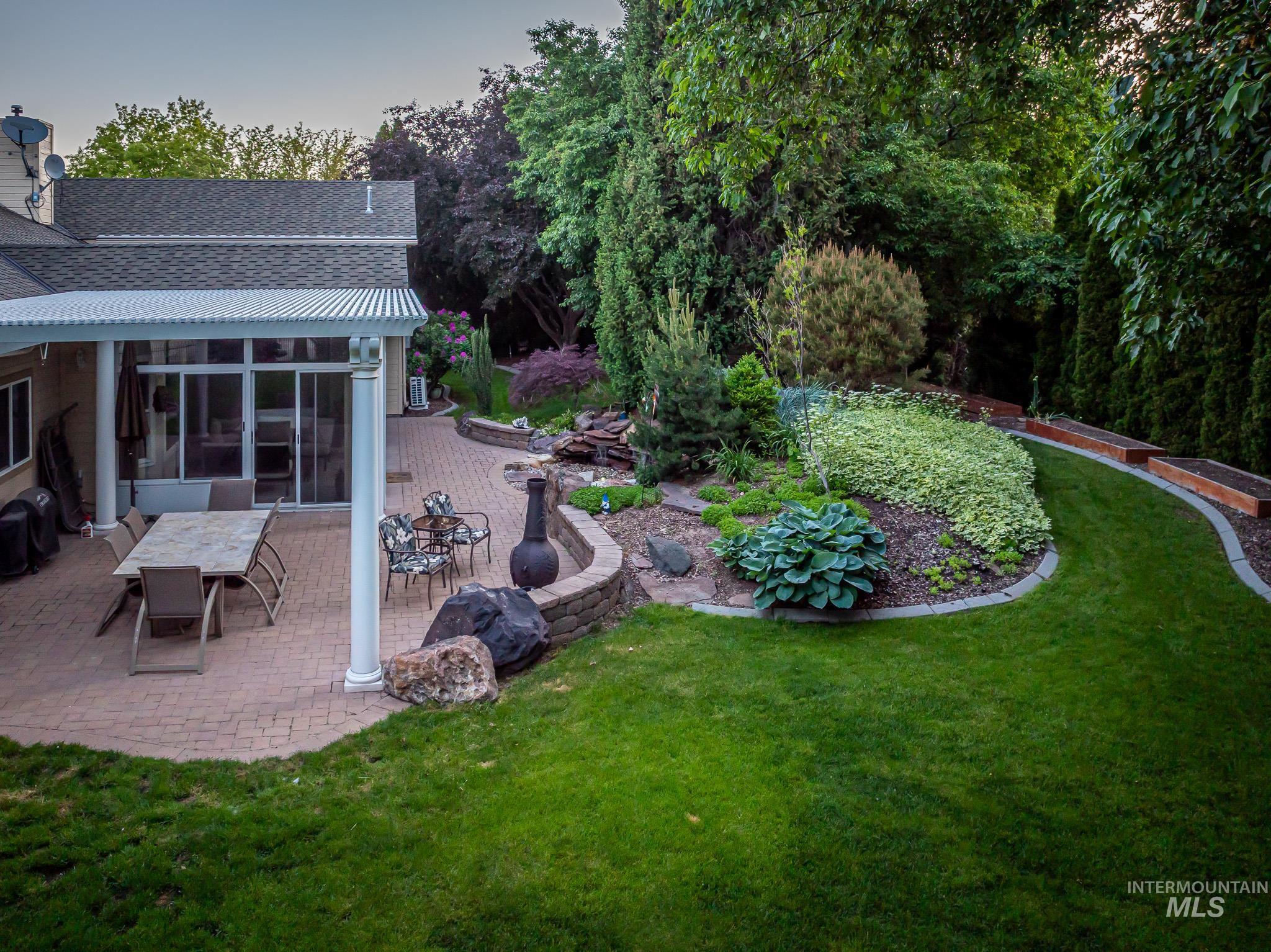 View of grassy yard with a sunroom, outdoor dining space, and a patio