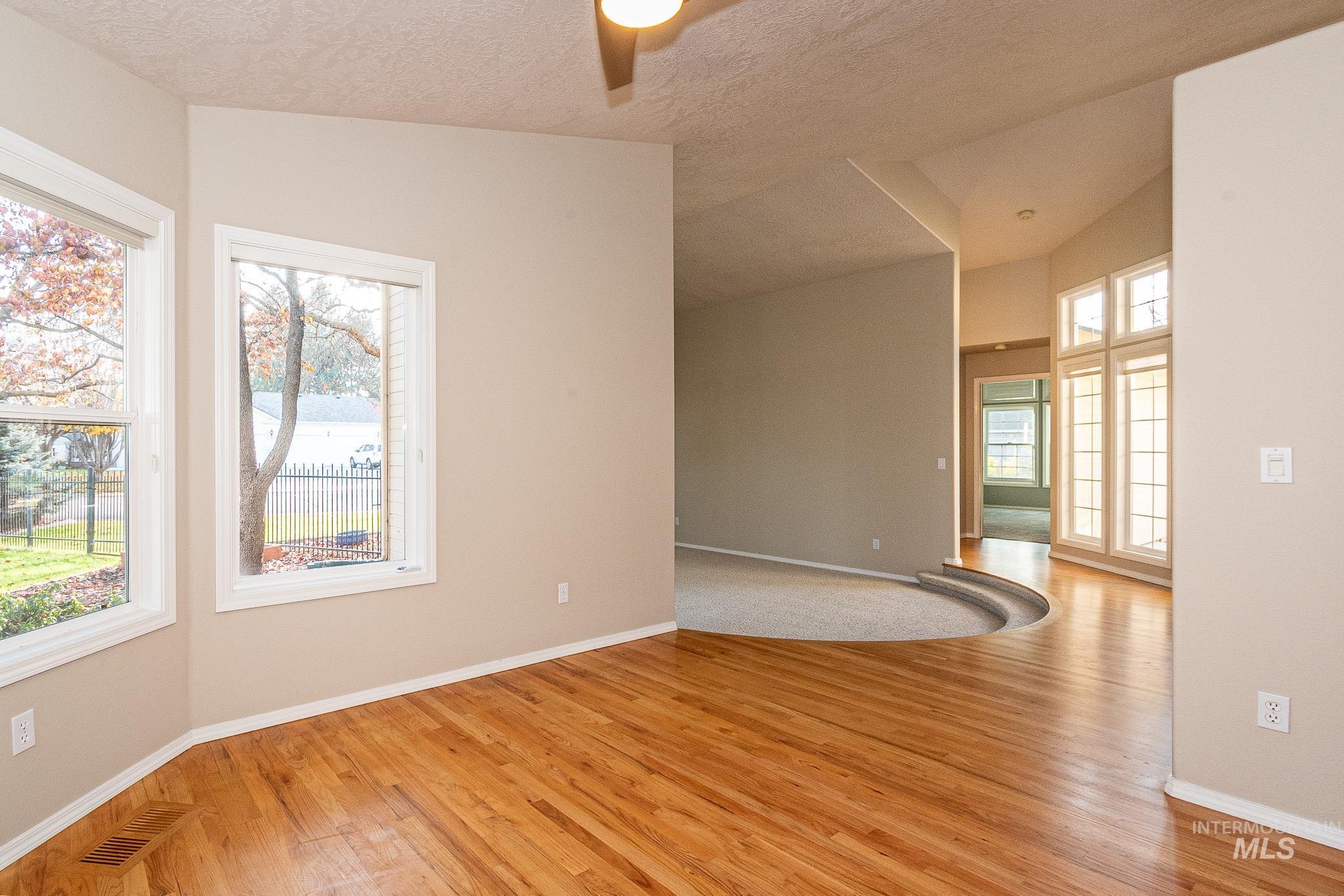 Unfurnished room with light wood-style floors, lofted ceiling, a textured ceiling, and ceiling fan