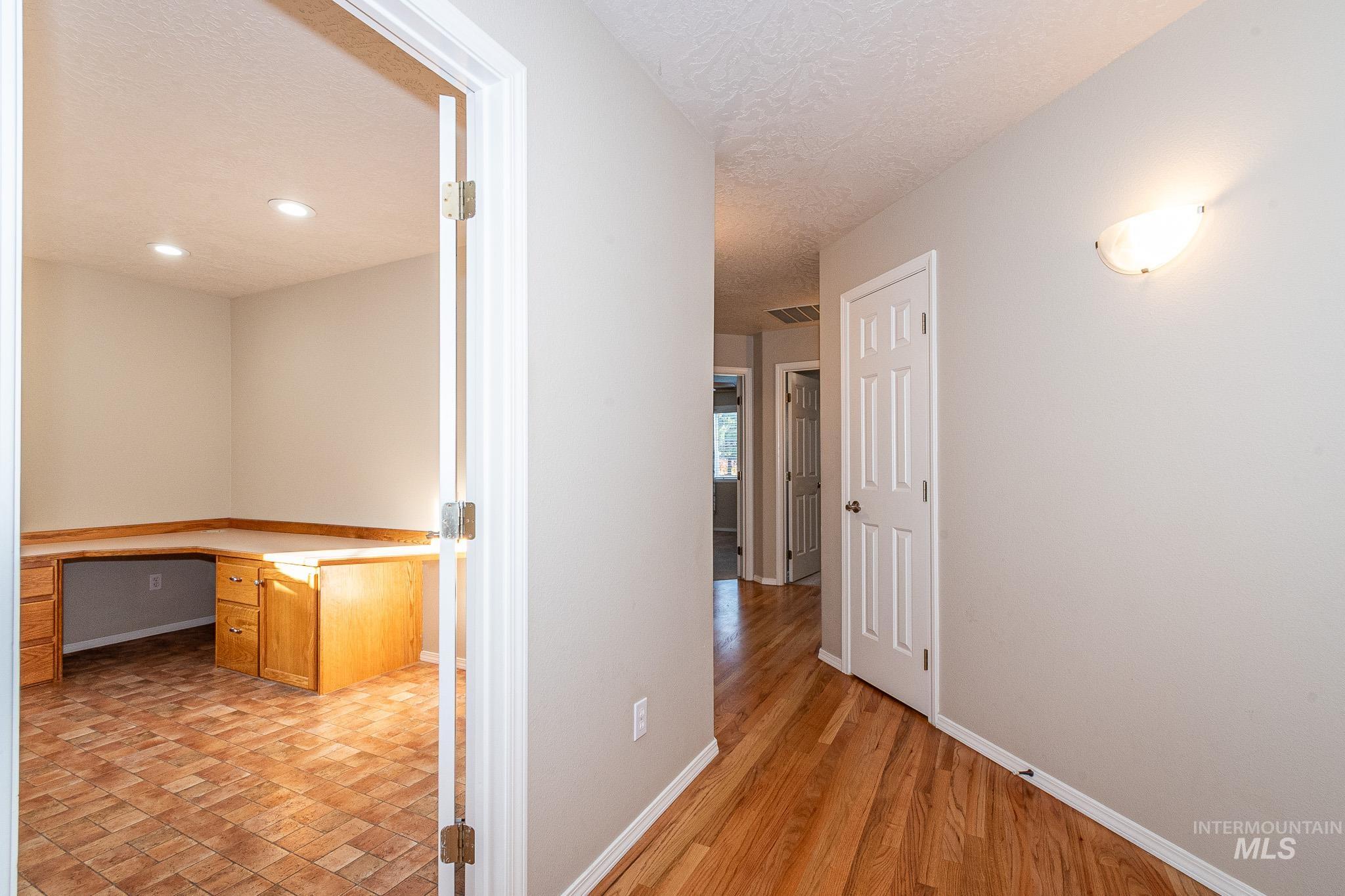 Hall featuring a desk, a textured ceiling, light wood-type flooring, and recessed lighting
