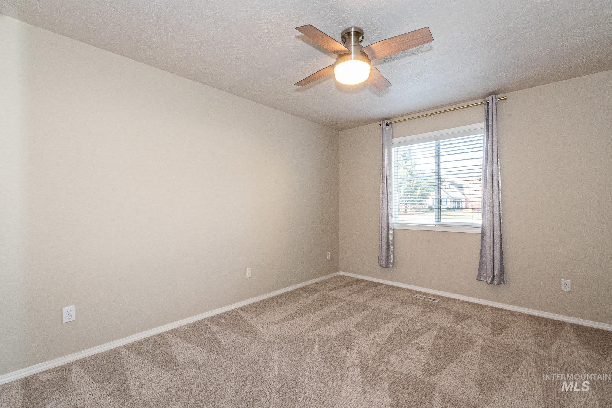 Carpeted spare room with a textured ceiling and ceiling fan
