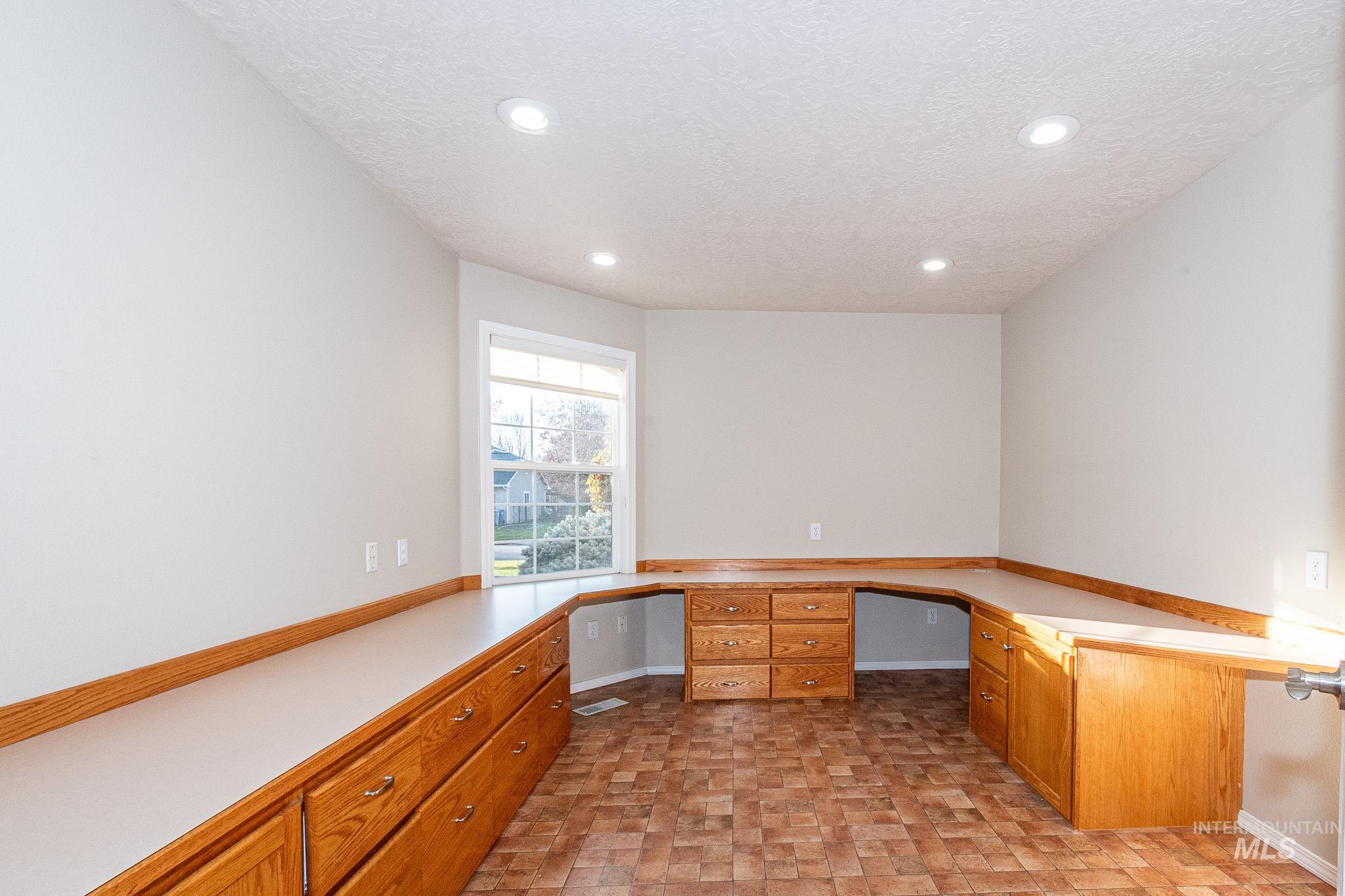 Unfurnished office with built in desk, a textured ceiling, and recessed lighting