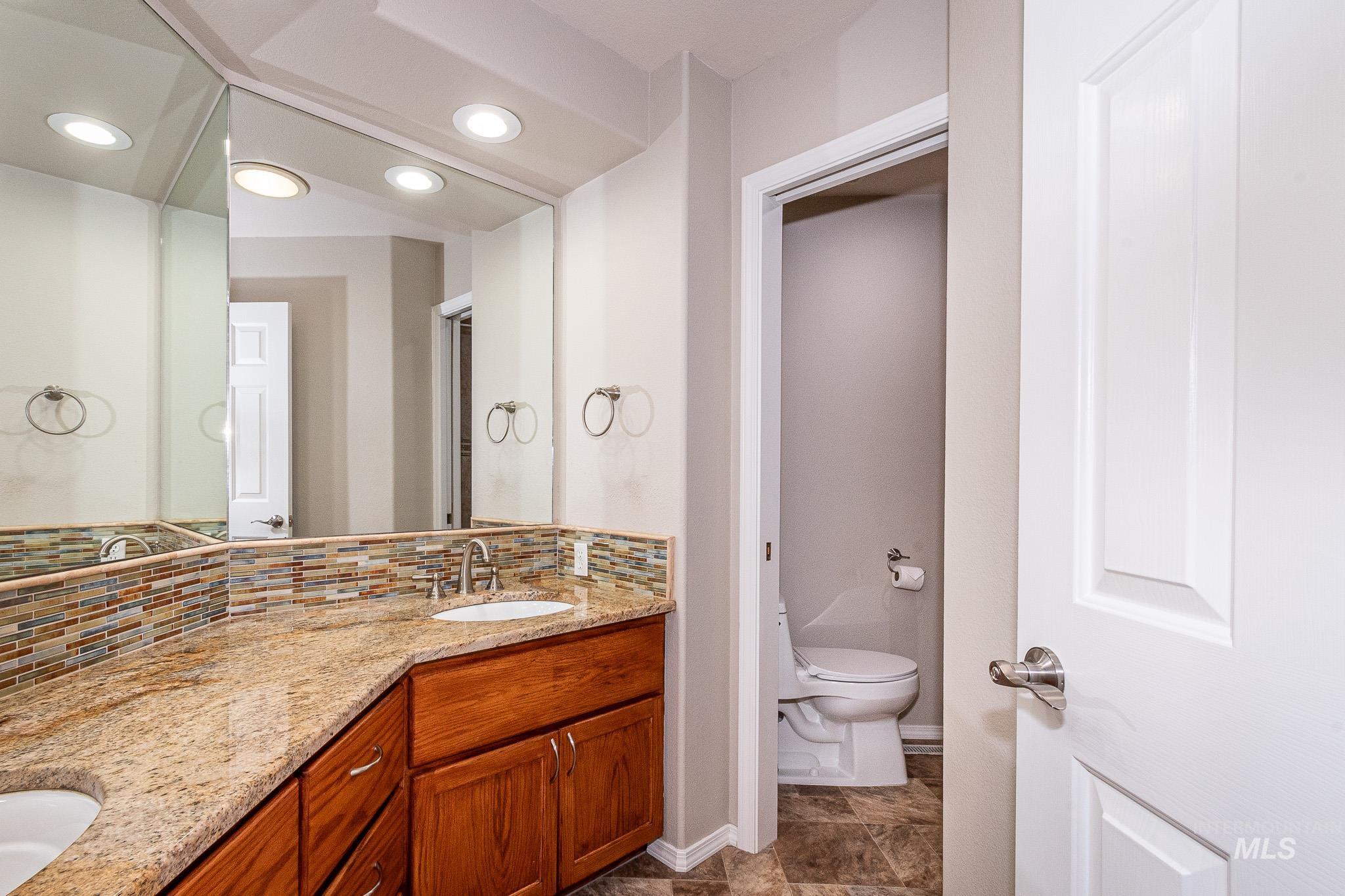 Full bathroom featuring decorative backsplash, double vanity, and recessed lighting
