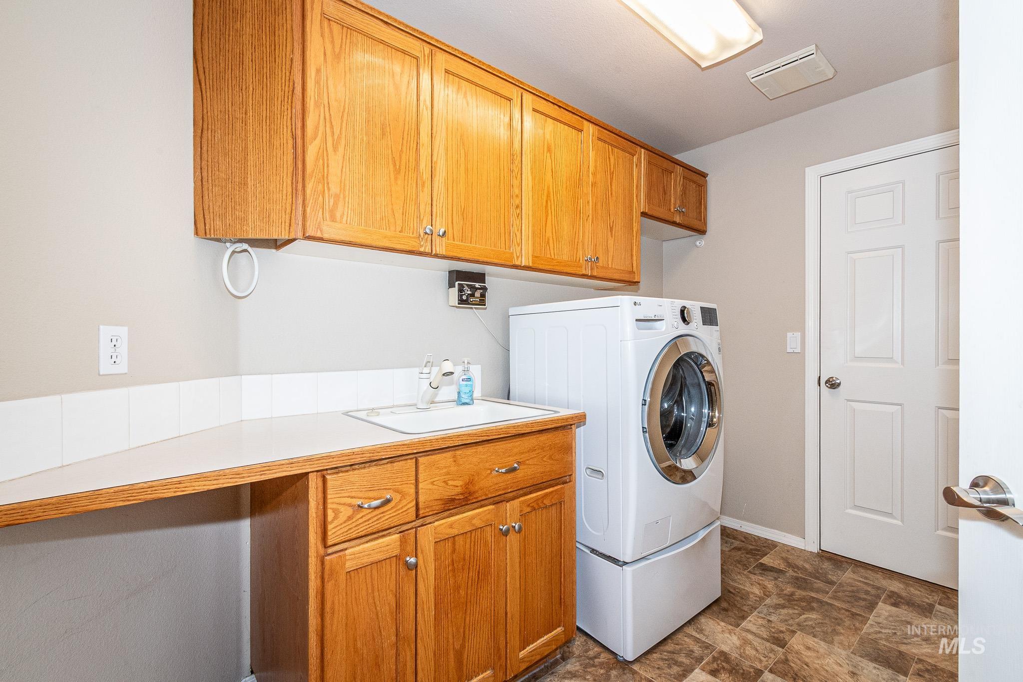 Laundry room featuring stone finish flooring, washer / dryer, and cabinet space