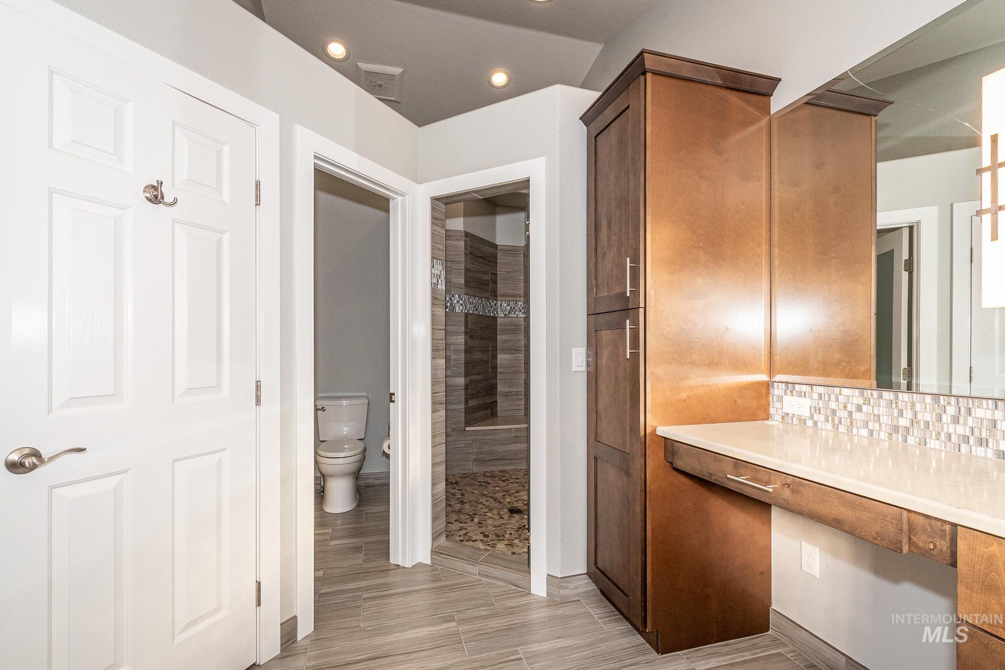 Bathroom with a shower stall, recessed lighting, backsplash, vanity, and wood tiled floors