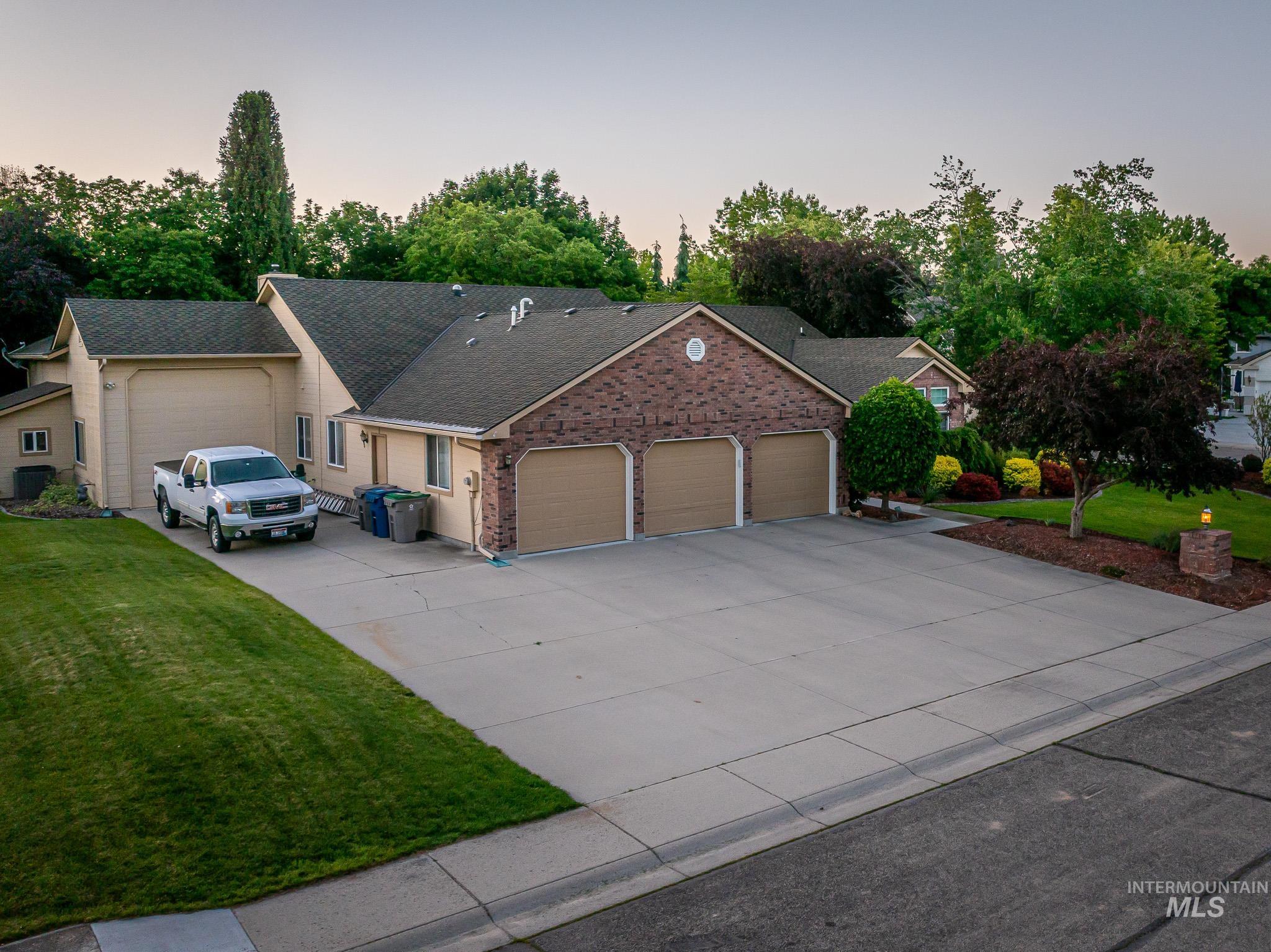 Ranch-style house with a yard, driveway, an attached garage, and a shingled roof
