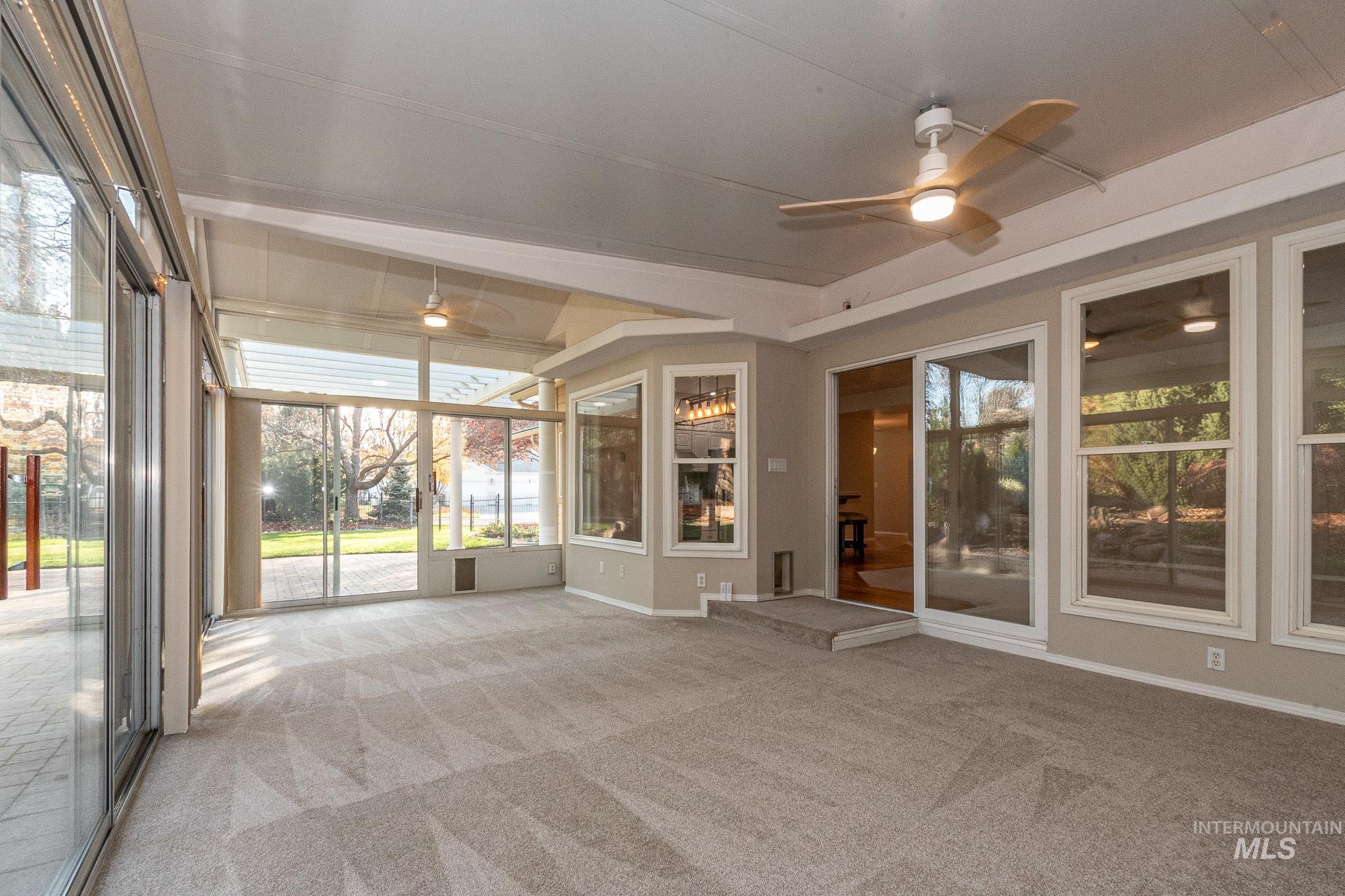 Unfurnished sunroom with ceiling fan and carpet floors