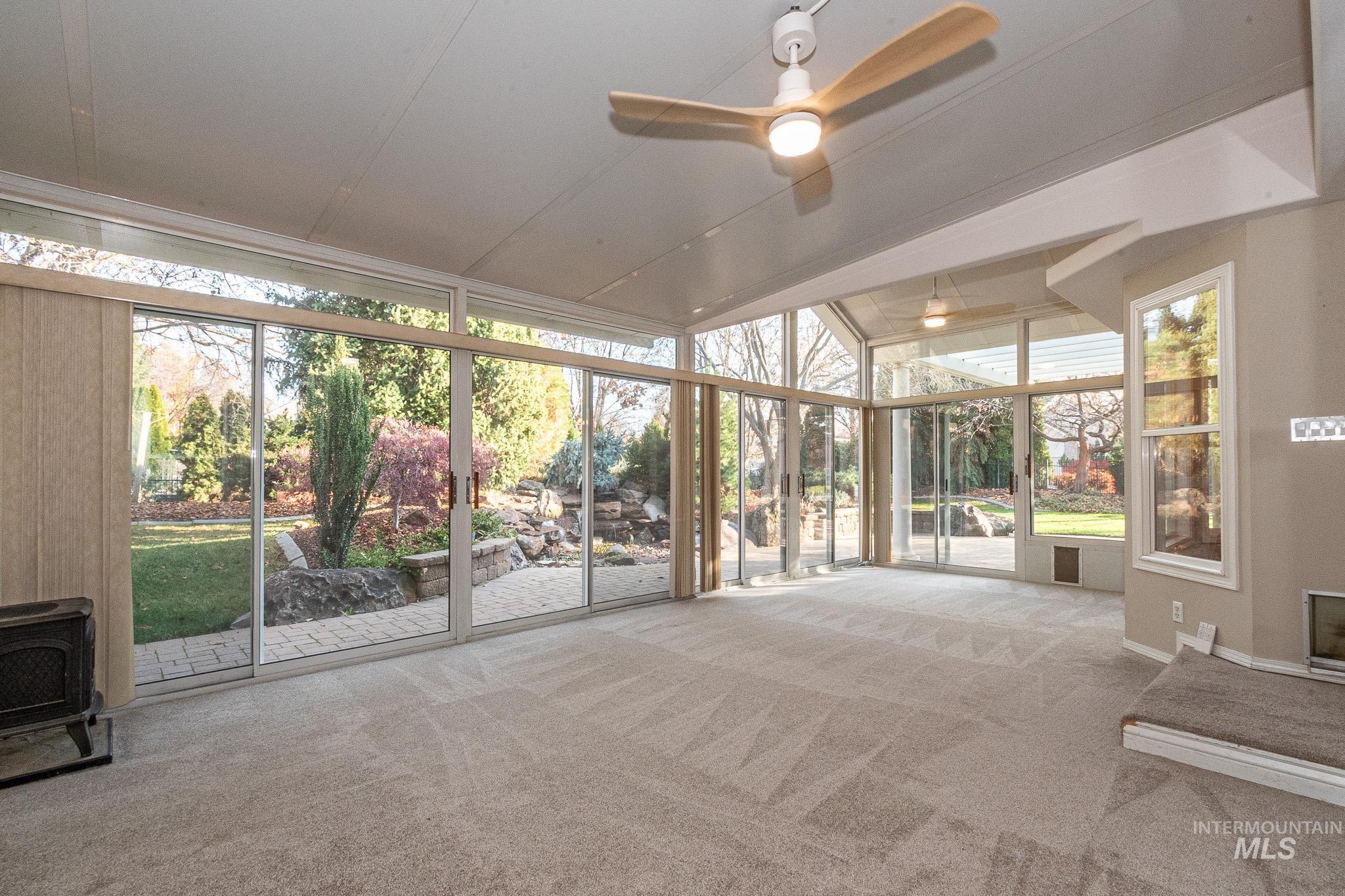 Unfurnished sunroom with expansive windows, carpet floors, and a wood stove