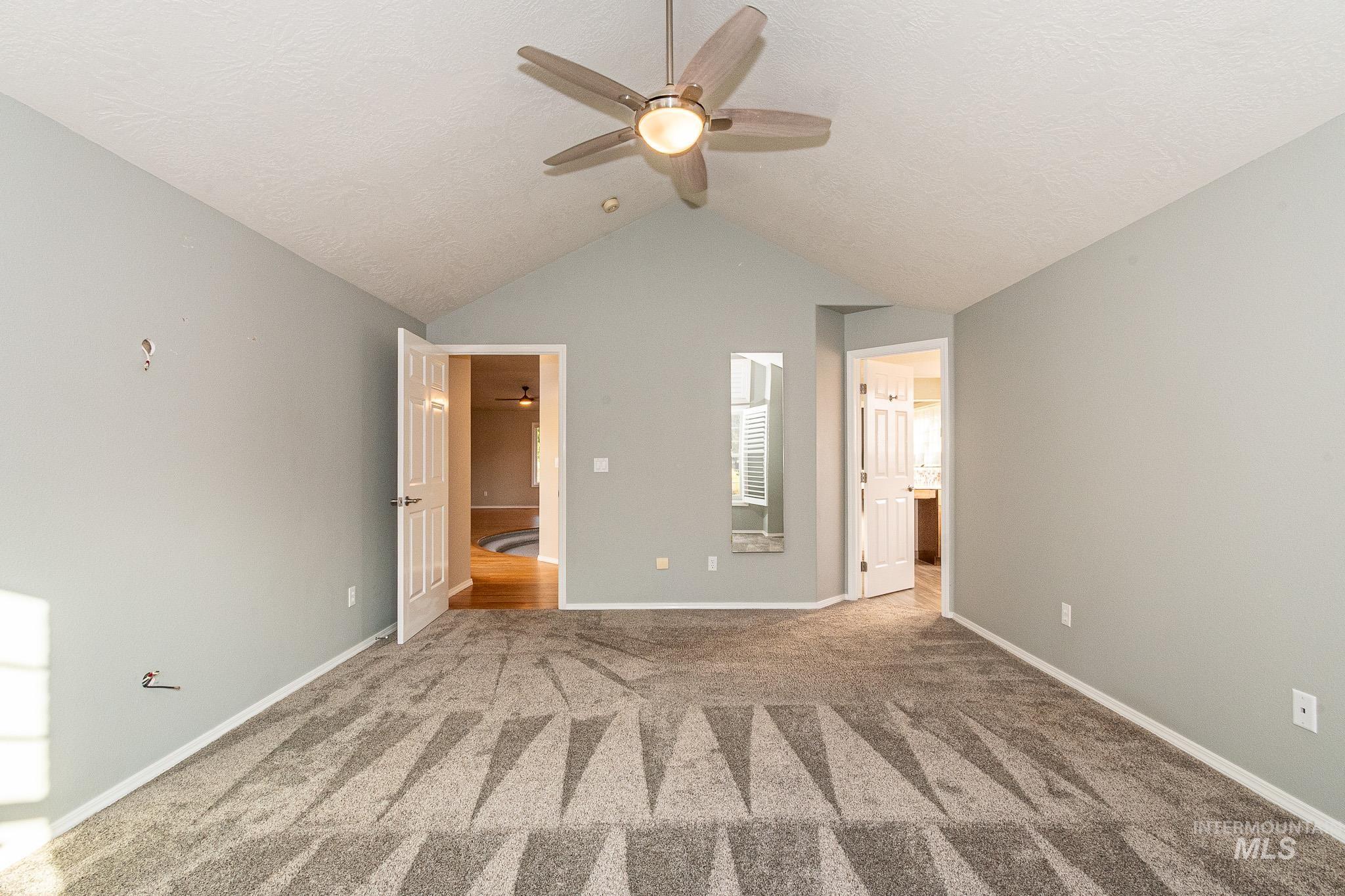 Unfurnished bedroom with carpet flooring, lofted ceiling, a ceiling fan, a textured ceiling, and connected bathroom