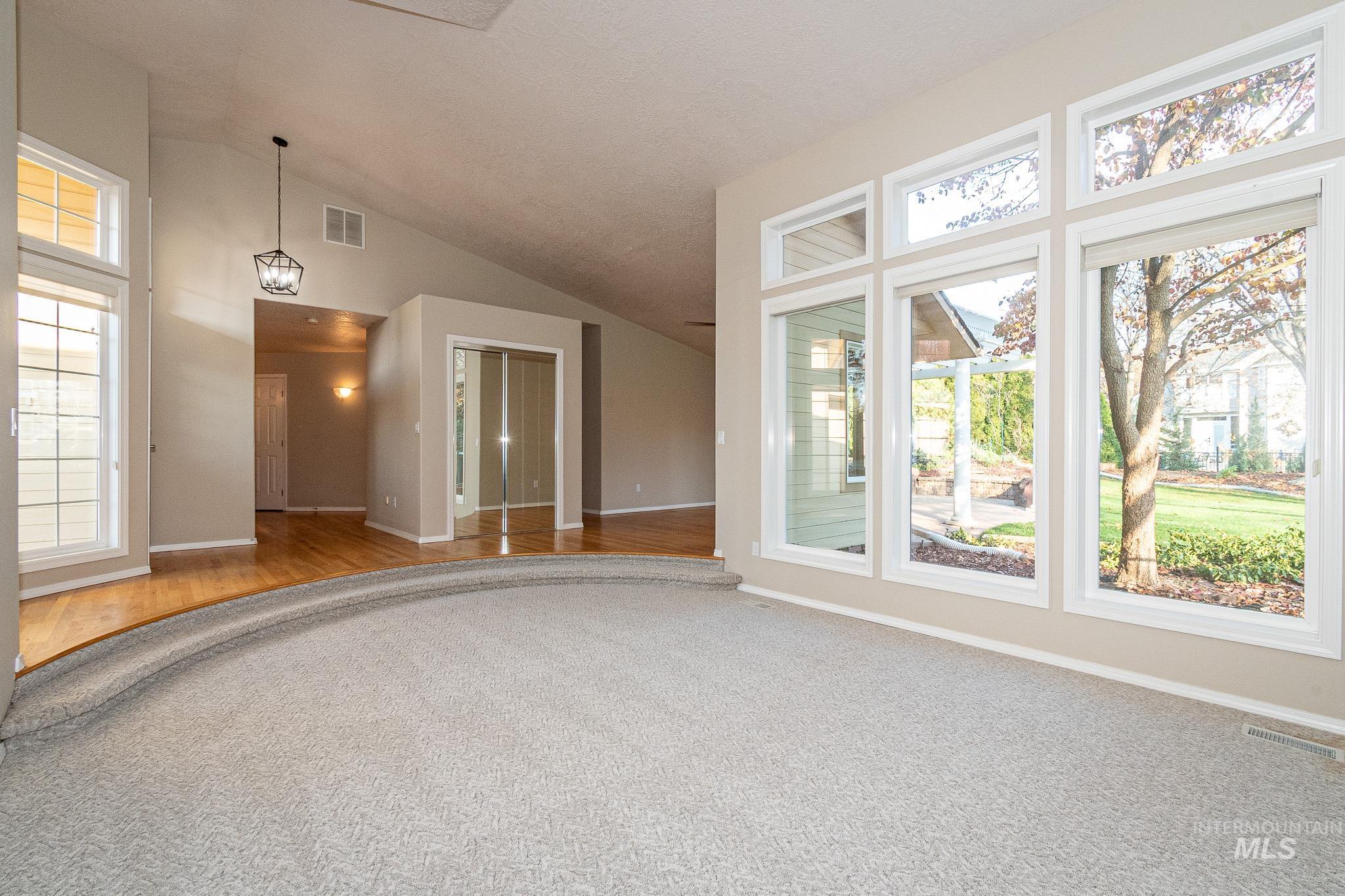 Carpeted empty room featuring vaulted ceiling and baseboards