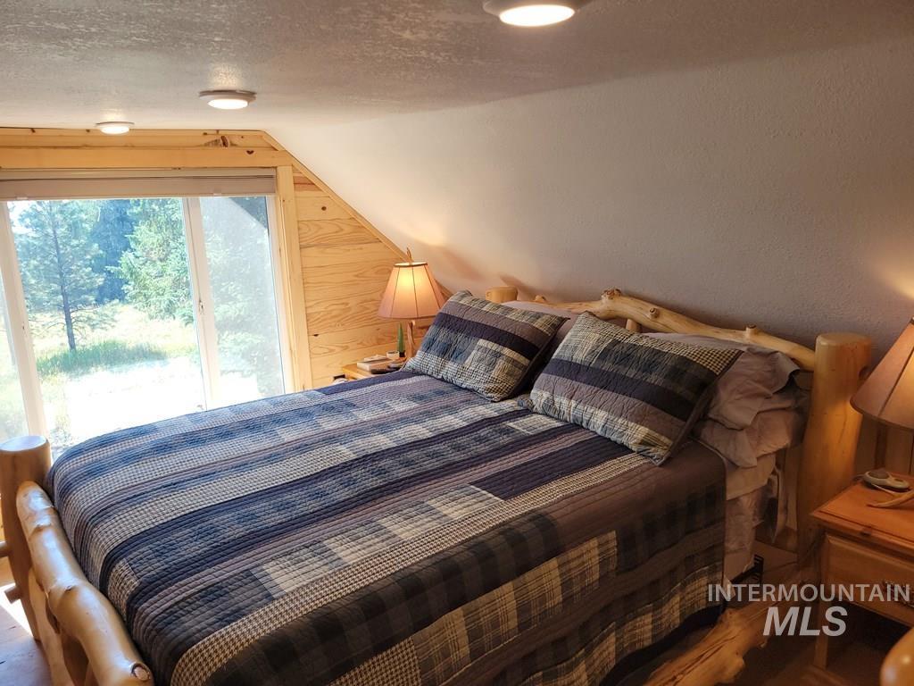 Bedroom with access to outside, a textured ceiling, and vaulted ceiling