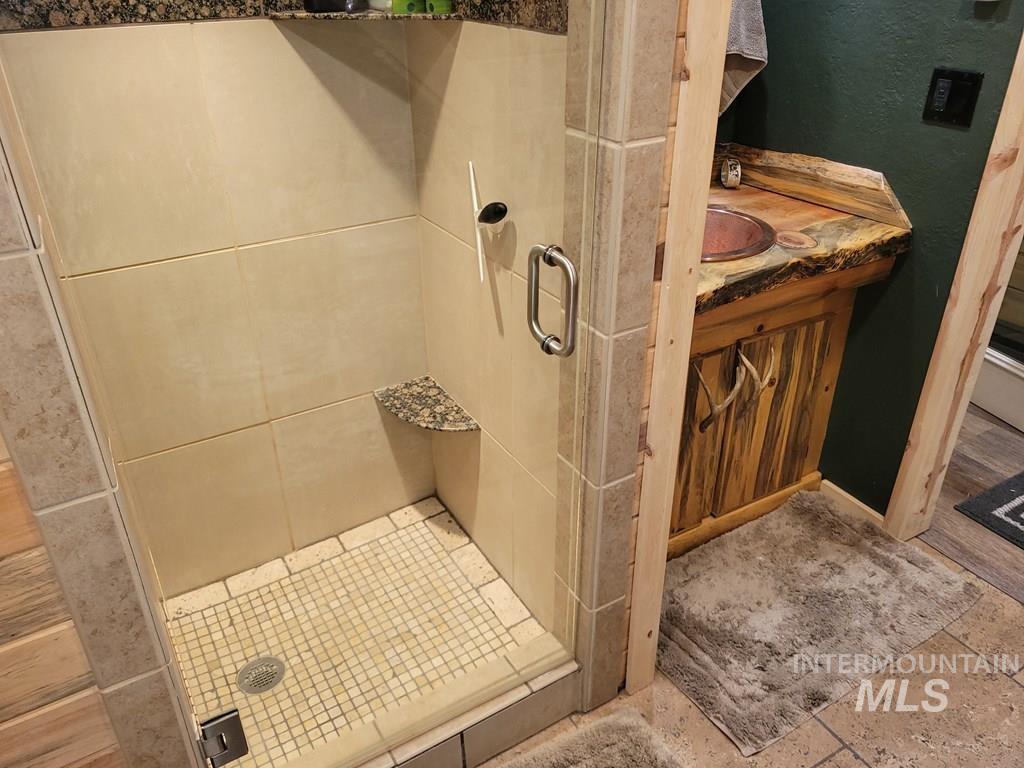 Bathroom featuring a shower stall, a textured wall, and vanity