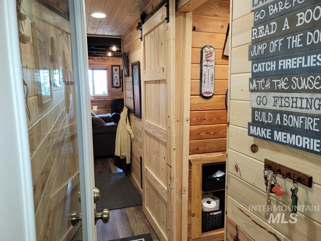 Hall with a barn door, wooden walls, and dark wood-type flooring