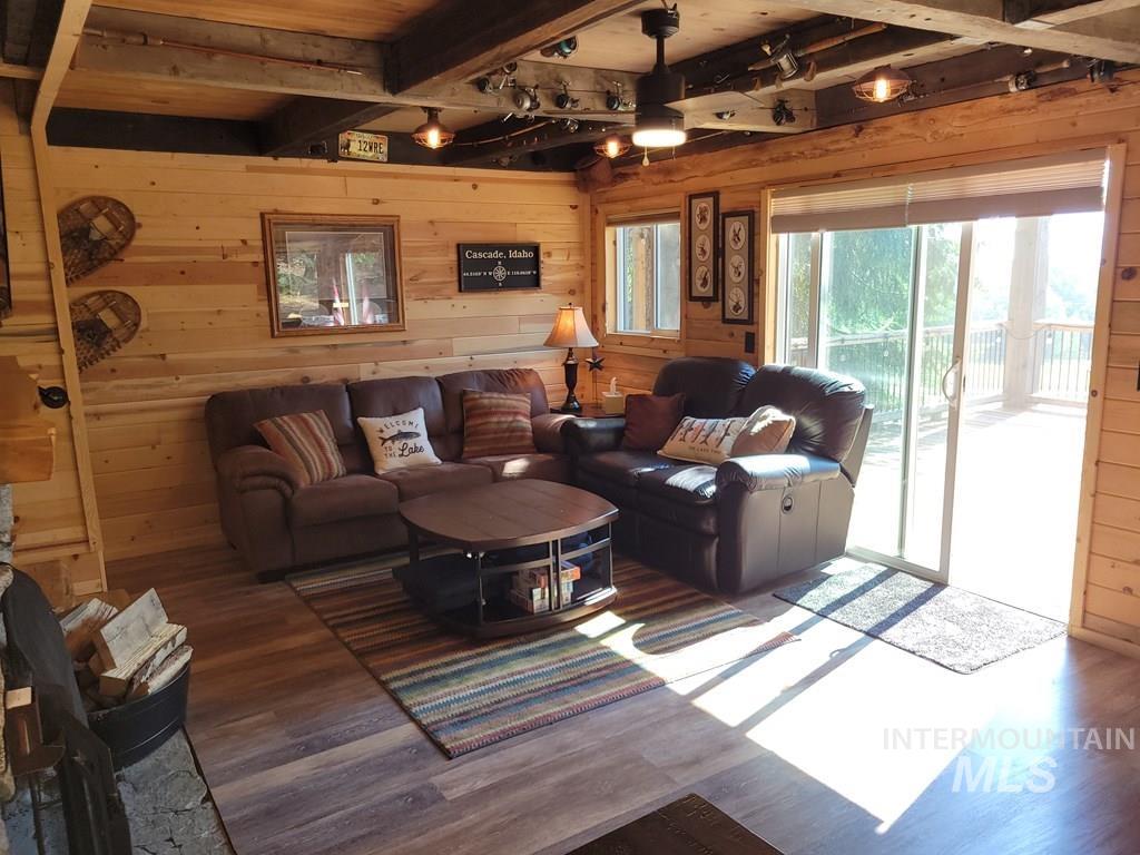 Living room with wood walls, beamed ceiling, and wood finished floors