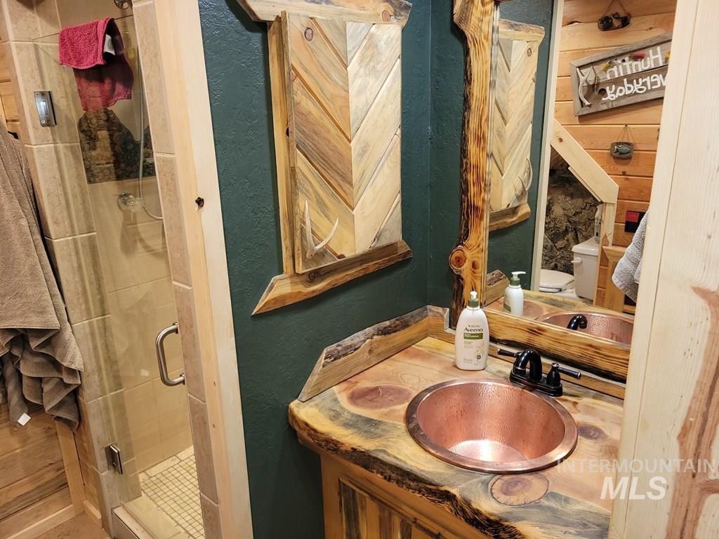Full bath featuring a textured wall, a shower stall, and vanity