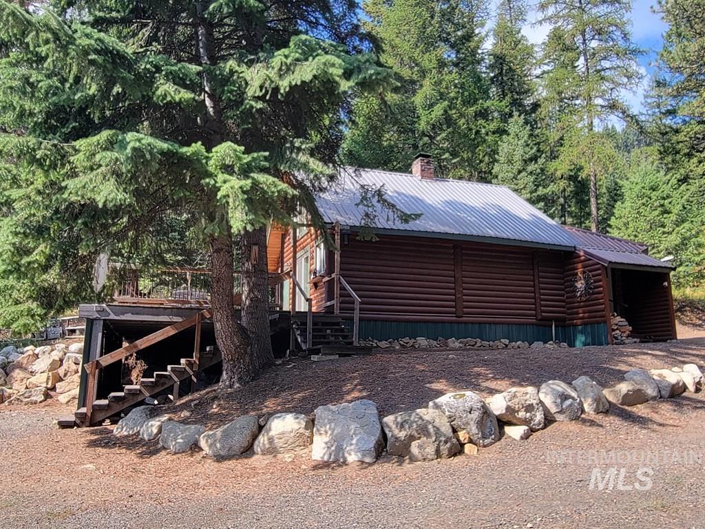 View of property exterior with stairway, faux log siding, a metal roof, and a wooden deck