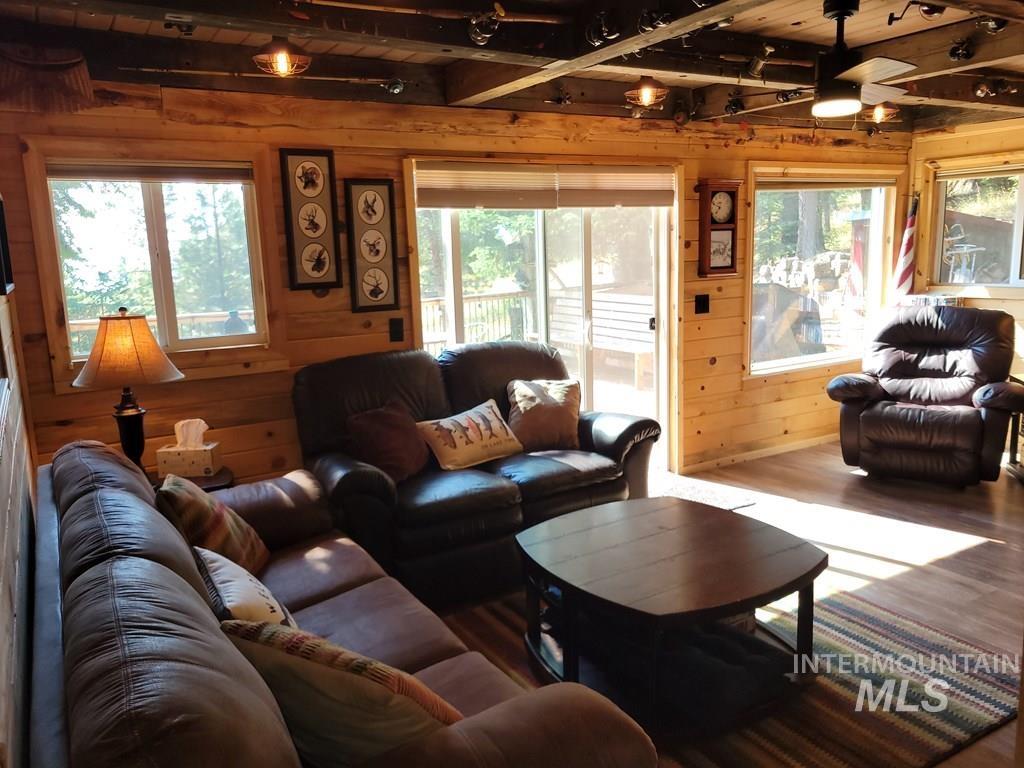 Living area with wood walls, wood finished floors, a ceiling fan, and a wood ceiling with exposed beams